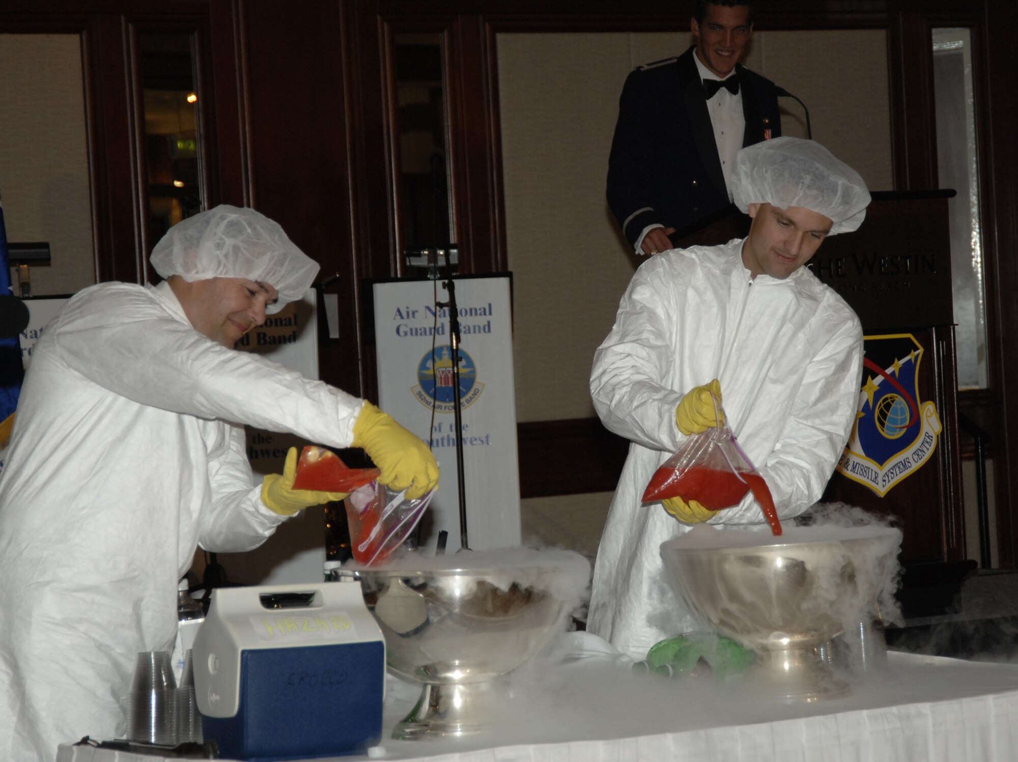 Major Kevin Crocco and Major Mark Hadley, both from the MILSATCOM Wing, donned clean room suits as they charged the “grog” with a secret ingredient from the Third Floor of Bldg. 271.  Several rules were laid out in the program and announced at the beginning of the evening. The penalty for breaking any of the rules, if caught, was a trip to the Grog Bowl. Approximately 600 people gathered at the Westin Hotel Ballroom in Long Beach Oct. 20 for this year’s Space and Missile Systems Center’s Dining Out. (Photo by Lou Hernandez)