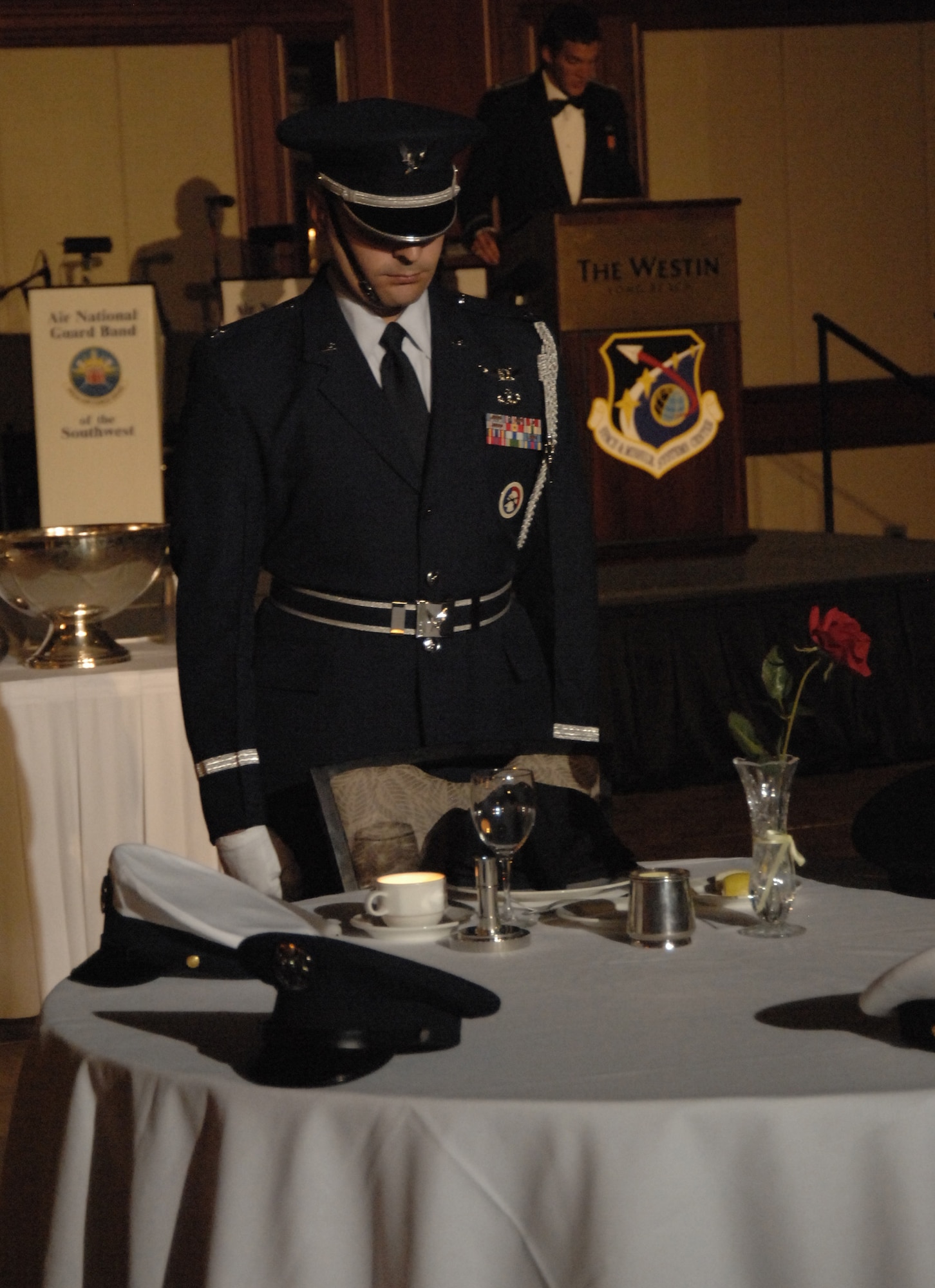 Capt Jim Manna, a member of the Los Angeles AFB Honor Guard from the SBIRS Wing, honors missing comrades in arms at this year’s Space and Missile Systems Center’s Dining Out.  The empty table represents Americans still missing from each of the five Armed Services.  This honors ceremony symbolizes that they are with us, here in spirit. (Photo by Lou Hernandez)