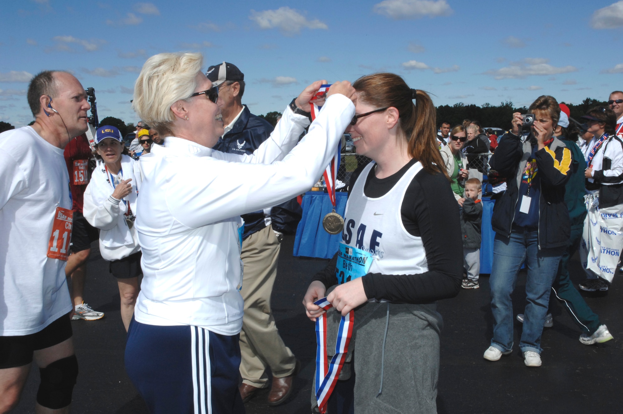 Having just completed the 11th annual U.S. Air Force Marathon's half-marathon race Sept. 15, Barbara Westgate, Air Force Materiel Command executive director, places a finisher's medal around her daughter, Beth Smith. In turn, Ms. Smith awarded her mother with her own medal. Mrs. Westgate dedicated herself to a 42-week program to train specifically for the race. In the process, she lost 44 pounds, and realized her rededication to wellness. (Air Force photo by Al Bright)
