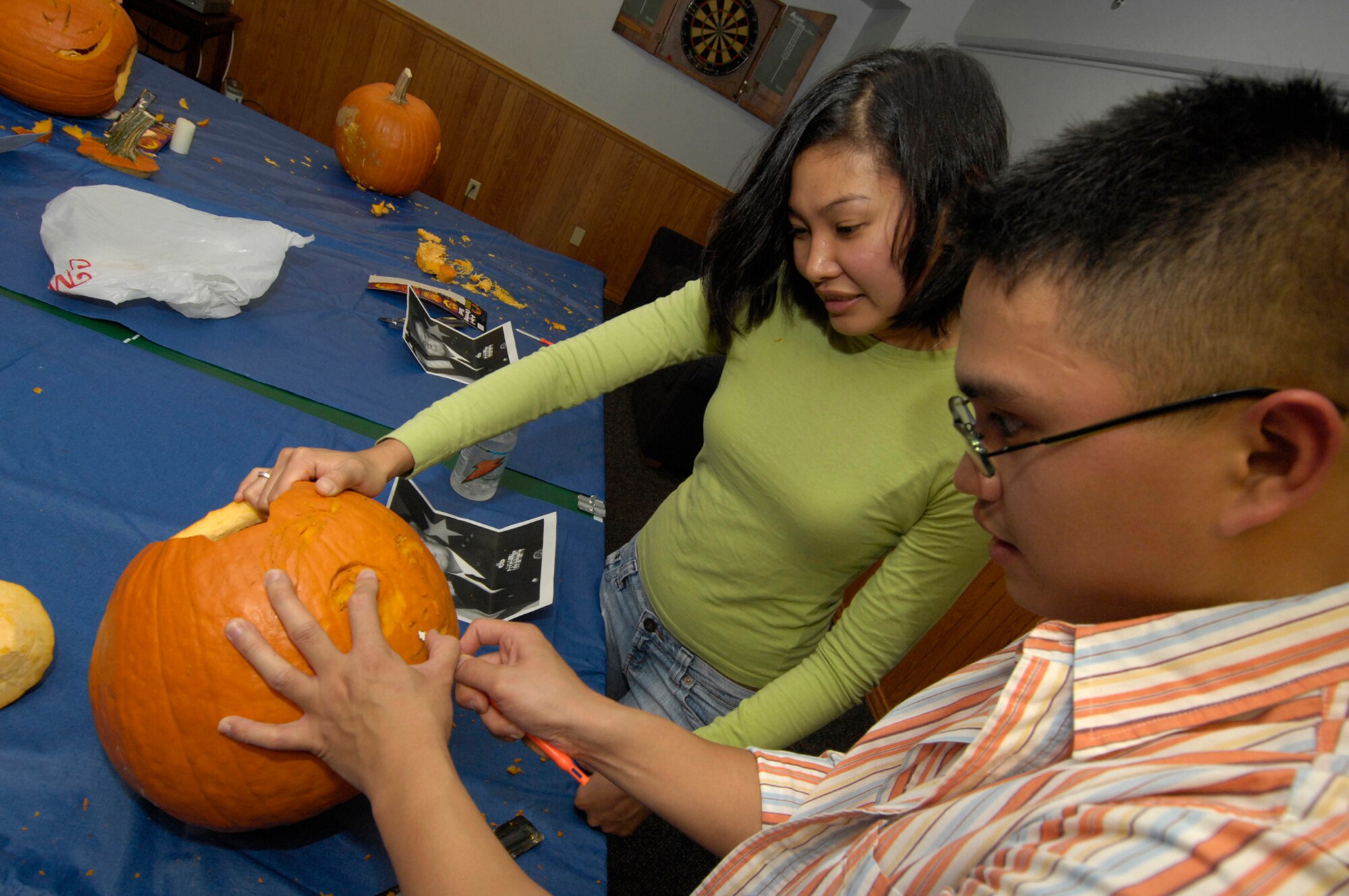 HANSCOM AFB, Mass. -- Airmen 1st Class Kristina Narabal (back), 66th Medical Operations Squadron dental technician, and Airman 1st Class Harold Pastoral, 66th Medical Support Squadron pharmacy technician, carve a pumpkin during a dorm dinner Oct. 23. (U.S. Air Force photo by Mark Wyatt.)