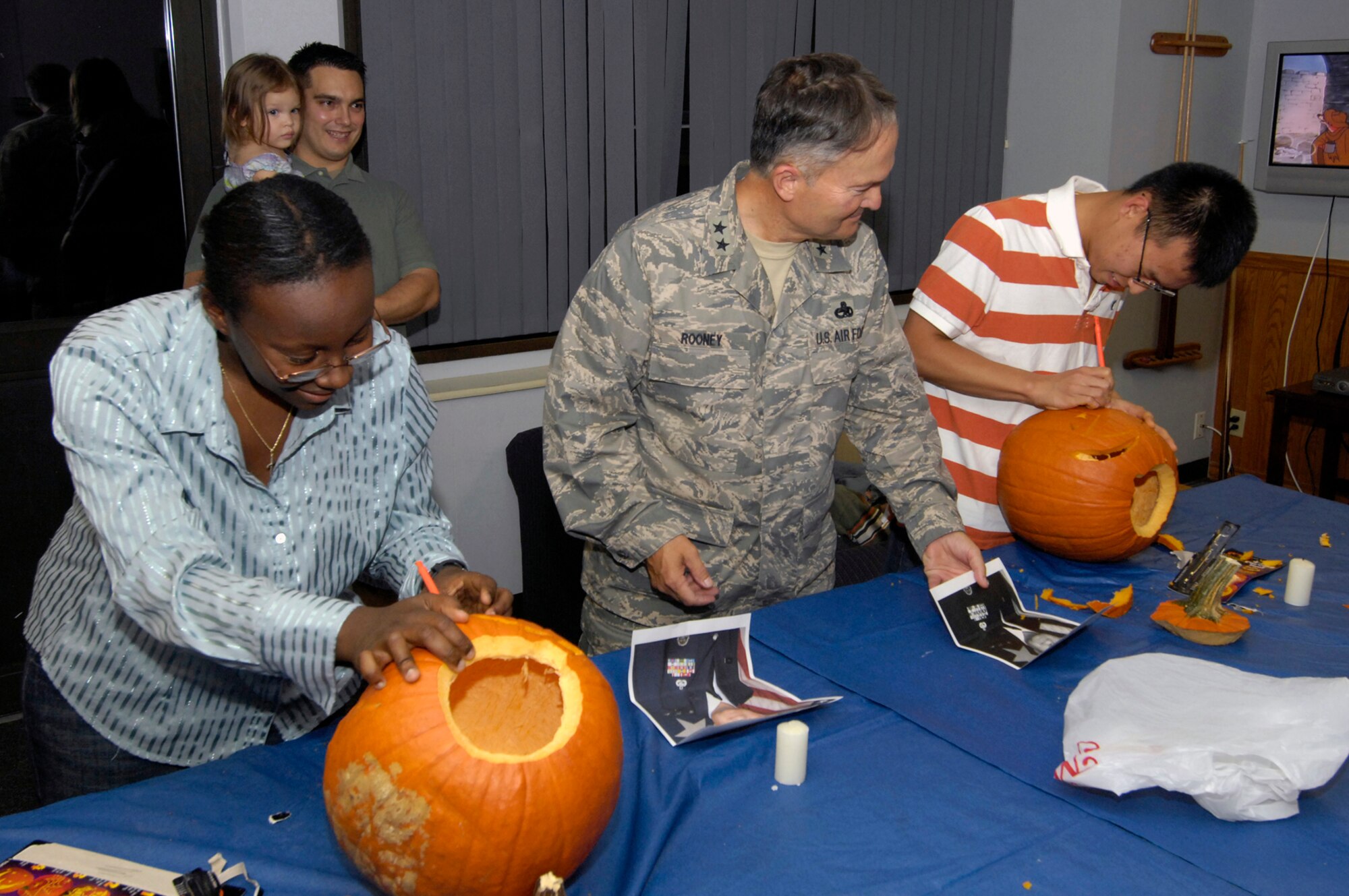 HANSCOM AFB, Mass. -- Airman First Class Latashia White (left), 753rd Electronic Systems Group, and Airman First Class Dong Li, 66th Medical Operations Squadron dental technician, carve pumpkins that try and resemble Retired Maj. Gen. Art Rooney (center). The pumpkin carving was part of a Dorm Dinner held Oct. 23. (U.S. Air Force photo by Mark Wyatt.)
