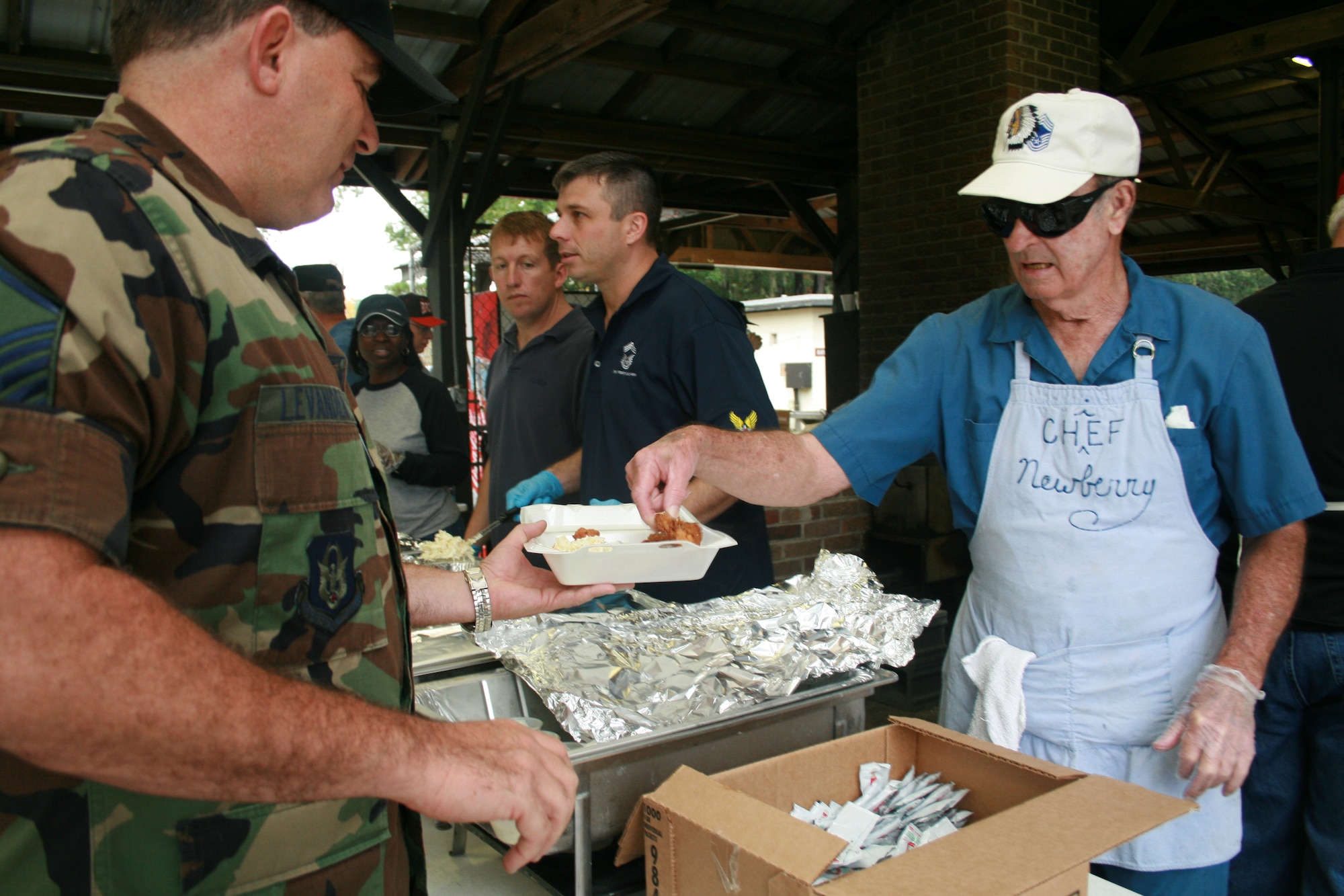Chief Master Sgt. (retired) James Newberry serves lunch to Master Sgt. Brad Levander, 81st Aerial Port Squadron, Charleston AFB, S.C., during the Charleston Chiefs group fish fry held at the base picnic grounds. (Photo by Kirsty Murray)