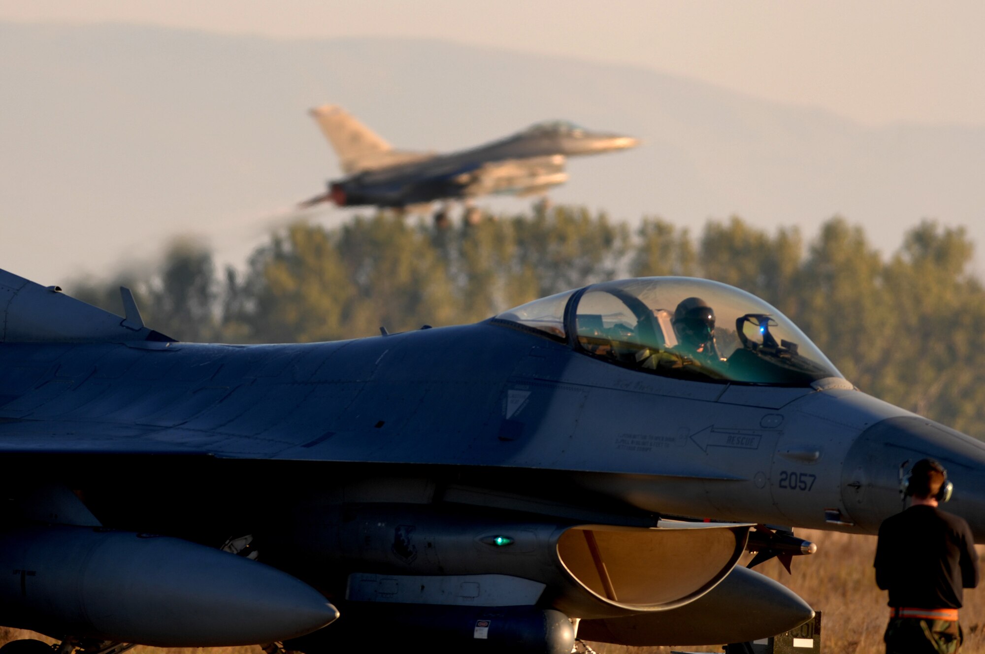 AVIANO AIR BASE, Italy--An F-16 prepares to taxi toward the end of runway while another F-16 takes off in the background at Graf Ignatevio air force base, Bulgaria.  250 Airman from Aviano join with Bulgarian air force to train together during Exercise RODOPI JAVELIN 2007 at Graf Ignatevio air force base, Bulgaria 5-26 Oct, 2007. (U.S. Air Force photo/Staff Sgt. Michael R. Holzworth)