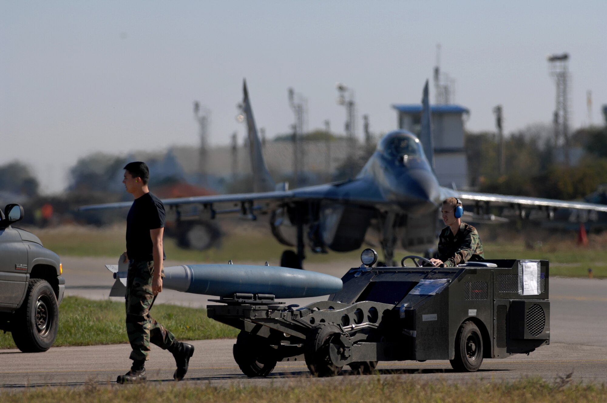AVIANO AIR BASE, Italy--Airman Mathew Fletcher drives a jammer vehicle with GBU-12 while Staff Sgt. Ski Weldone guides the GBU-12 toward the F-16 for loading, while a MiG-29 taxis toward the end of the runway.  250 Airman from Aviano join with Bulgarian air force to train together during Exercise RODOPI JAVELIN 2007 at Graf Ignatevio air force base, Bulgaria. 5-26 Oct, 2007.  (U.S. Air Force photo/Staff Sgt. Michael R. Holzworth)