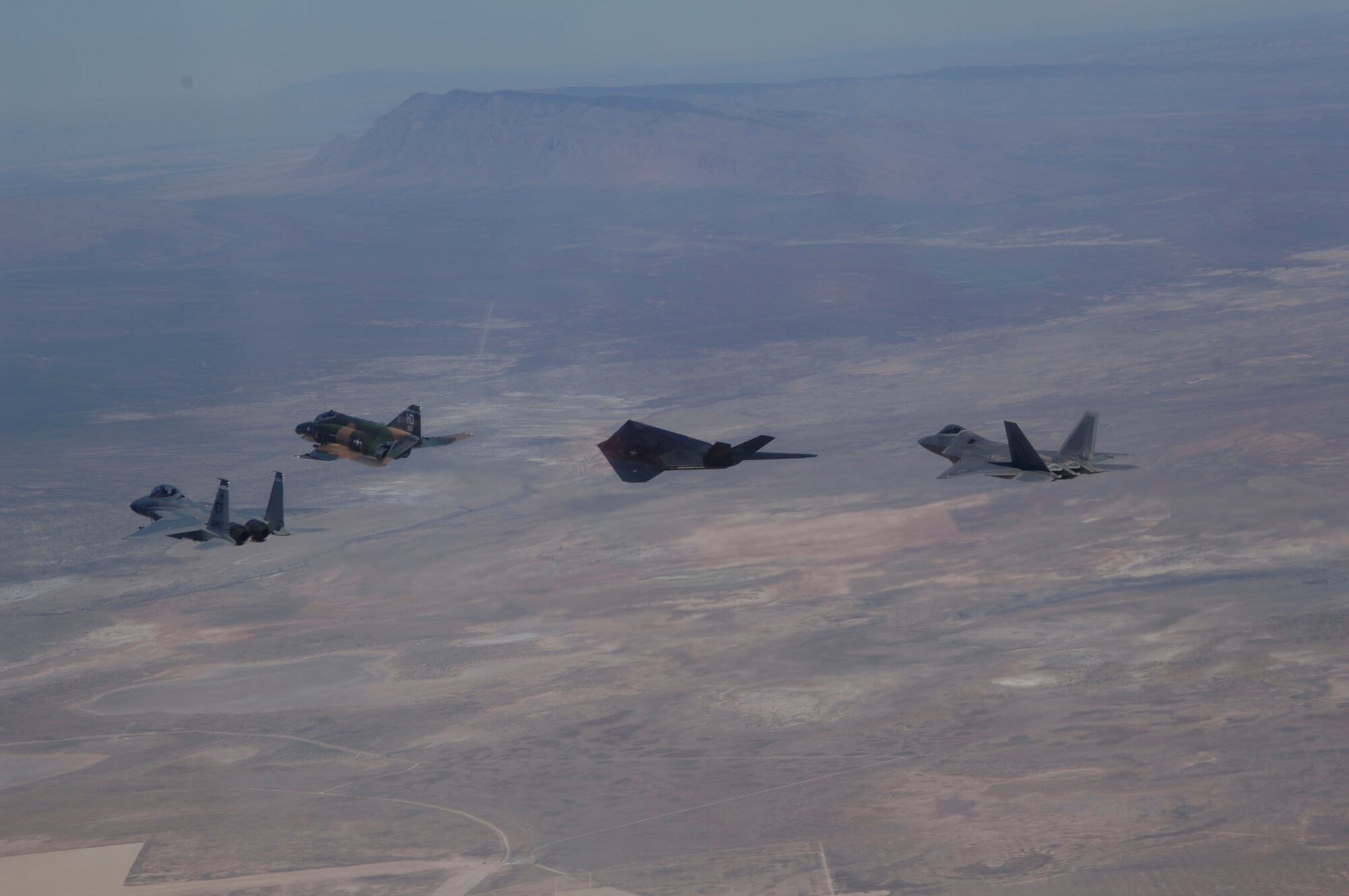 An F-15 Eagle, F-4 Phantom, F-117 Nighthawk, and F-22 Raptor fly in formation over Holloman Air Force Base, NM during the Holloman Air and Space Expo on October 27, 2007. The HASE is a showcase of Air Force capabilities, the 49th Fighter Wing mission and the X Prize Foundation. (U.S. Air Force photo by Senior Airman Russell Scalf)