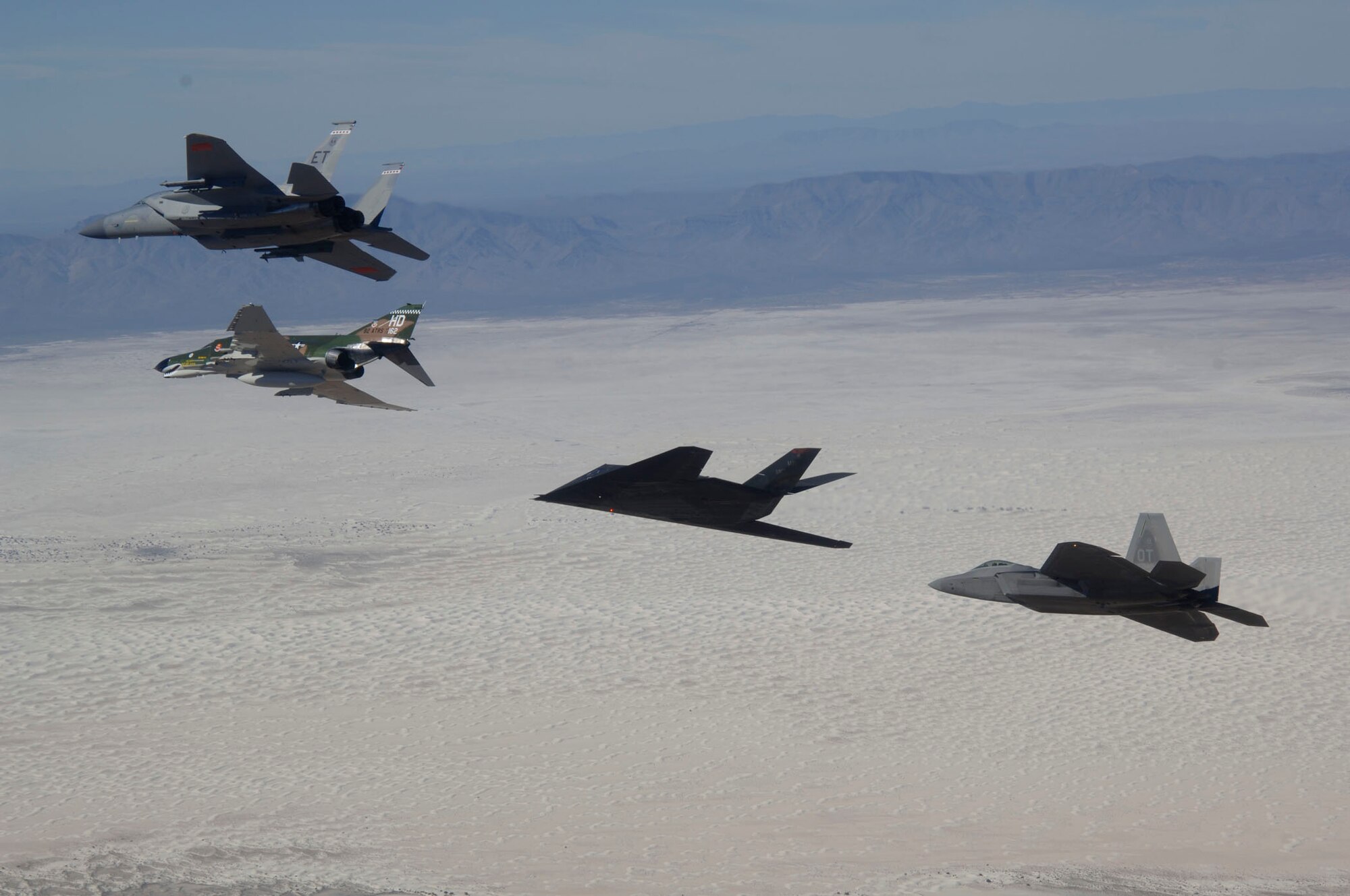 An F-15 Eagle, F-4 Phantom, F-117 Nighthawk, and F-22 Raptor fly in formation over Holloman Air Force Base, NM during the Holloman Air and Space Expo on October 27, 2007. The HASE is a showcase of Air Force capabilities, the 49th Fighter Wing mission and the X Prize Foundation. (U.S. Air Force photo by Senior Airman Russell Scalf)