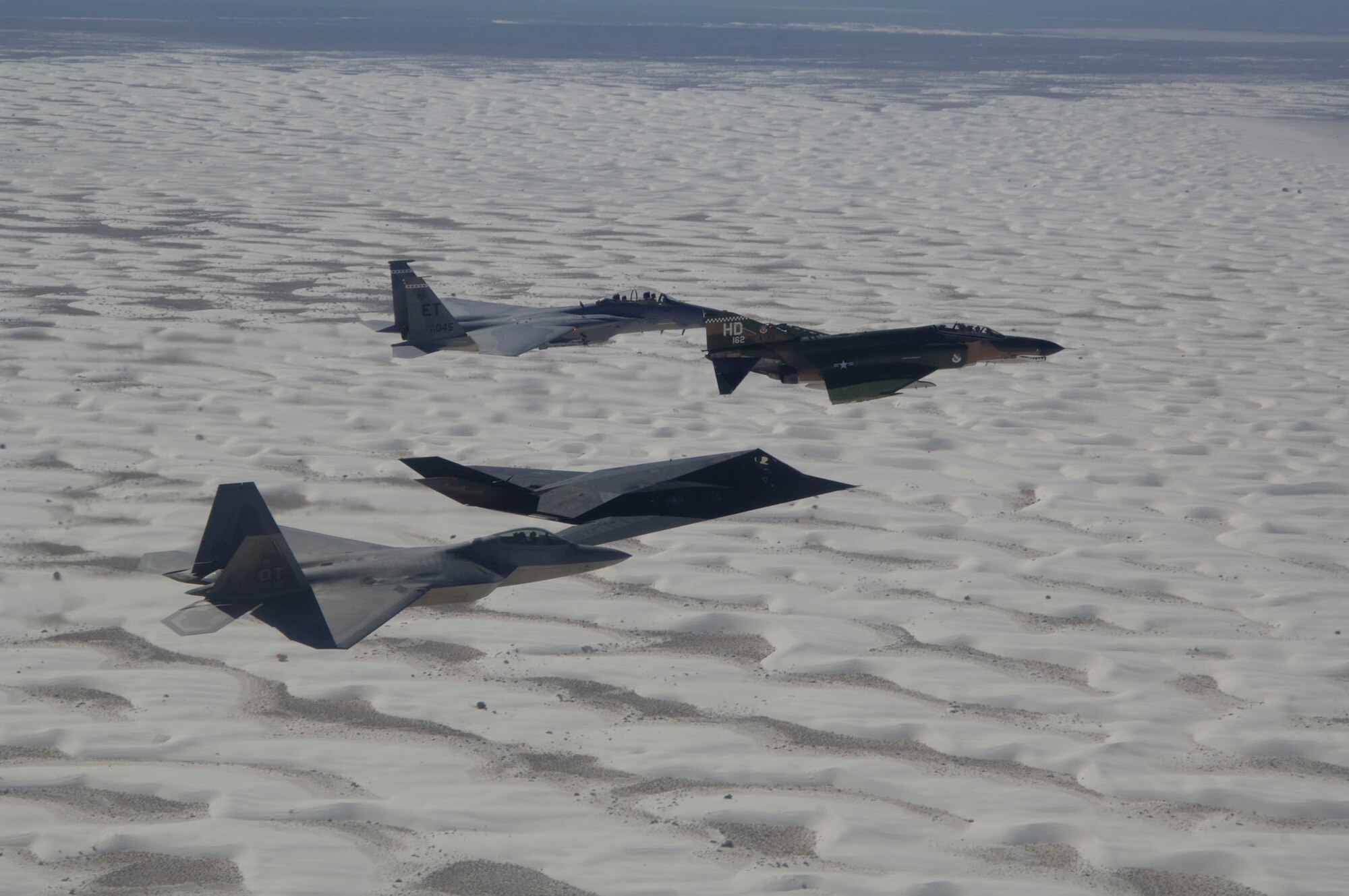 An F-15 Eagle, F-4 Phantom, F-117 Nighthawk, and F-22 Raptor fly in formation over Holloman Air Force Base, NM during the Holloman Air and Space Expo on October 27, 2007. The HASE is a showcase of Air Force capabilities, the 49th Fighter Wing mission and the X Prize Foundation. (U.S. Air Force photo by Senior Airman Russell Scalf)