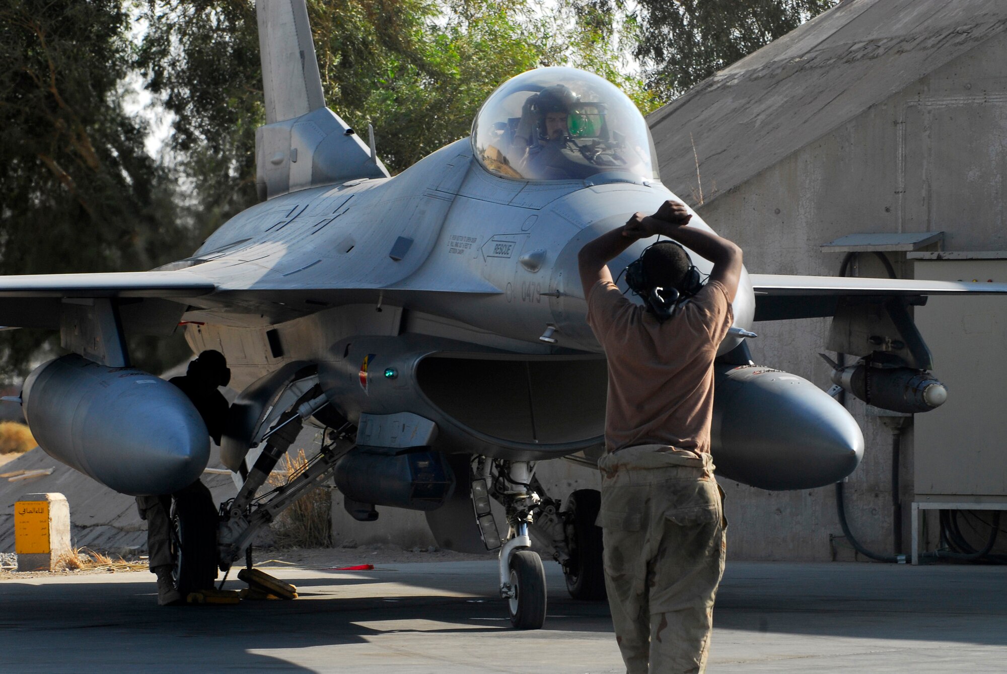 BALAD AIR BASE, Iraq -- Airman 1st Class Martin Johnson, 332nd Expeditionary Aircraft Maintenance Squadron crew chief, uses hand signals to tell Capt. Thomas "Shack" Graham, 4th Expeditionary Fighter Squadron, to standby for the chalks to be removed from under his aircraft. Communication between the pilot and maintenance personnel is essential in ensuring safety. Both Captain Graham and Airman Johnson are deployed from Hill Air Force Base, Utah.  (U.S. Air Force photo/Staff Sgt. Joshua Garcia)