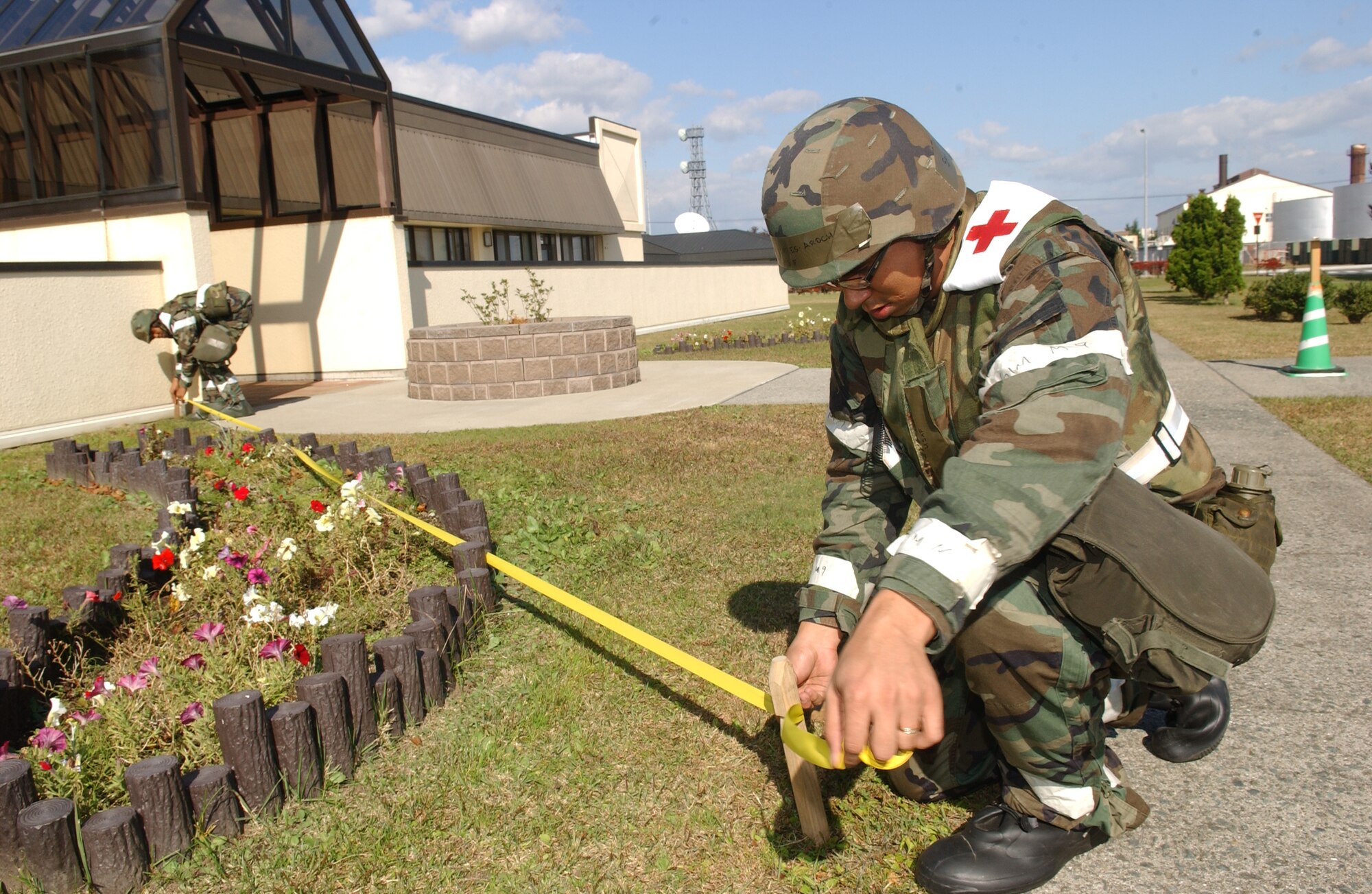 MISAWA AIR BASE, Japan -- Senior Airman Jose Torres-Arocho (Right) and Airman 1st Class Tatiana Swann (Left) tie down yellow tape to cordon off the area where a simulated unexploded ordinance was found just outside building 99 on Oct. 23, 2007 during exercise Beverly Sunrise 08-01.  This exercise is designed to assess the base's war fighting capabilities. (U.S. Air Force photo by Senior Airman Robert Barnett)(RELEASED)
