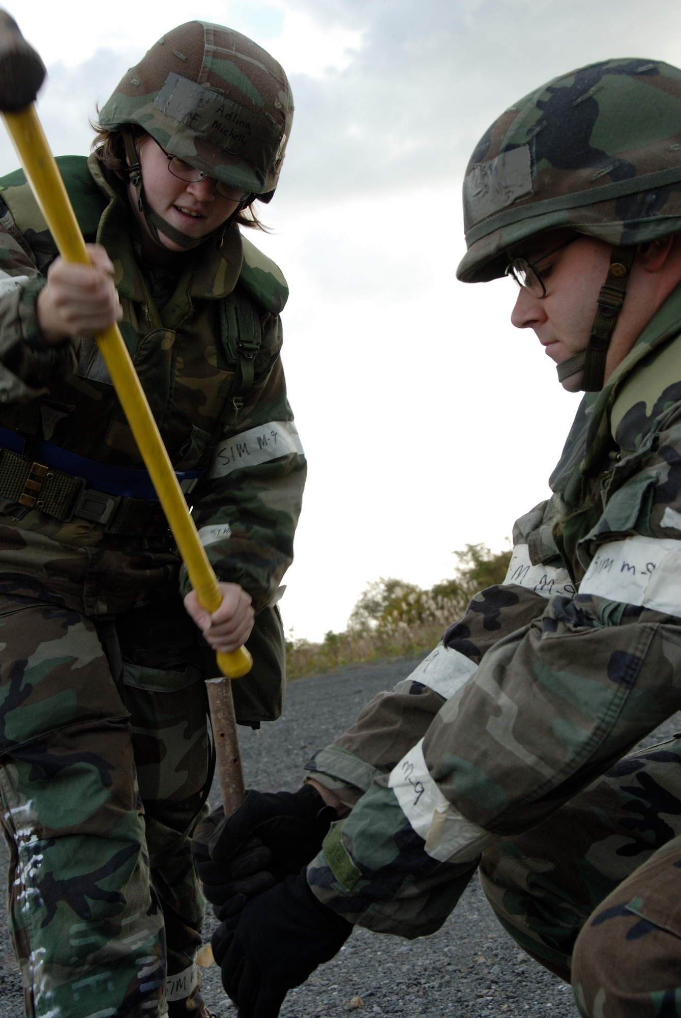 MISAWA AIR BASE, Japan -- Staff Sgt. Ryan Dickelman holds a stake tightly as Staff Sgt. Michelle Adling pounds down on a stake setting the perimeter of a berm for a water bladder on Oct. 23, 2007 during exercise Beverly Sunrise 08-01.  A berm is mound of earth placed to provide protection to vital assets.  Sergeants Dickelman and Adling are assigned to the 35th Civil Engineering Squadron.  This exercise was designed to assess the base's war fighting capabilities.  (U.S. Air Force photo by Senior Airman Laura R. McFarlane)(RELEASED)