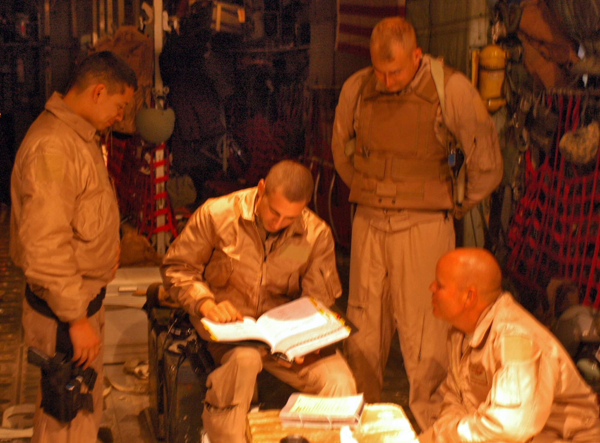 SOUTHWEST ASIA - Airman 1st Class Jacob Medina (left), Tech. Sgt. Kevin Letz (back right), and Senior Master Sgt. Jerry Bohl (lower right) are briefed by Senior Airman William Moody (center sitting), all from the 40th Expeditionary Airlift Squadron, on proper safety precautions and procedures for an air drop mission prior to take off. Pre-briefing the crew ensures that everyone will know what to do and when to do it so that there are no mishaps durign the flight. (U.S. Air Force photo/Staff Sgt. Jason Barebo)
