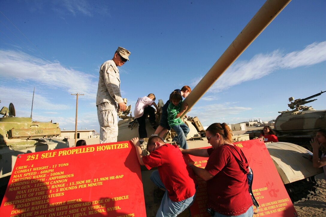 Capt. Stanton Lee supervises children as they climb aboard military vehicles during a Kids Care event. The children were visiting and passed out candy bags to Marines training in Mojave Viper Monday.