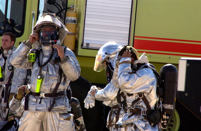 Airmen from the 99th Civil Engineer Fire Protection Flight don their equipment in preparation for the live fire exercise Oct. 17, Nellis AFB Nev.  The exercise, that must be done once a year by every Firefighter, tests the Airmens skills in combating both an exterior and interior fire on an aircraft(U.S.Air Force photo by Airman 1st Class Ryan Whitney) 