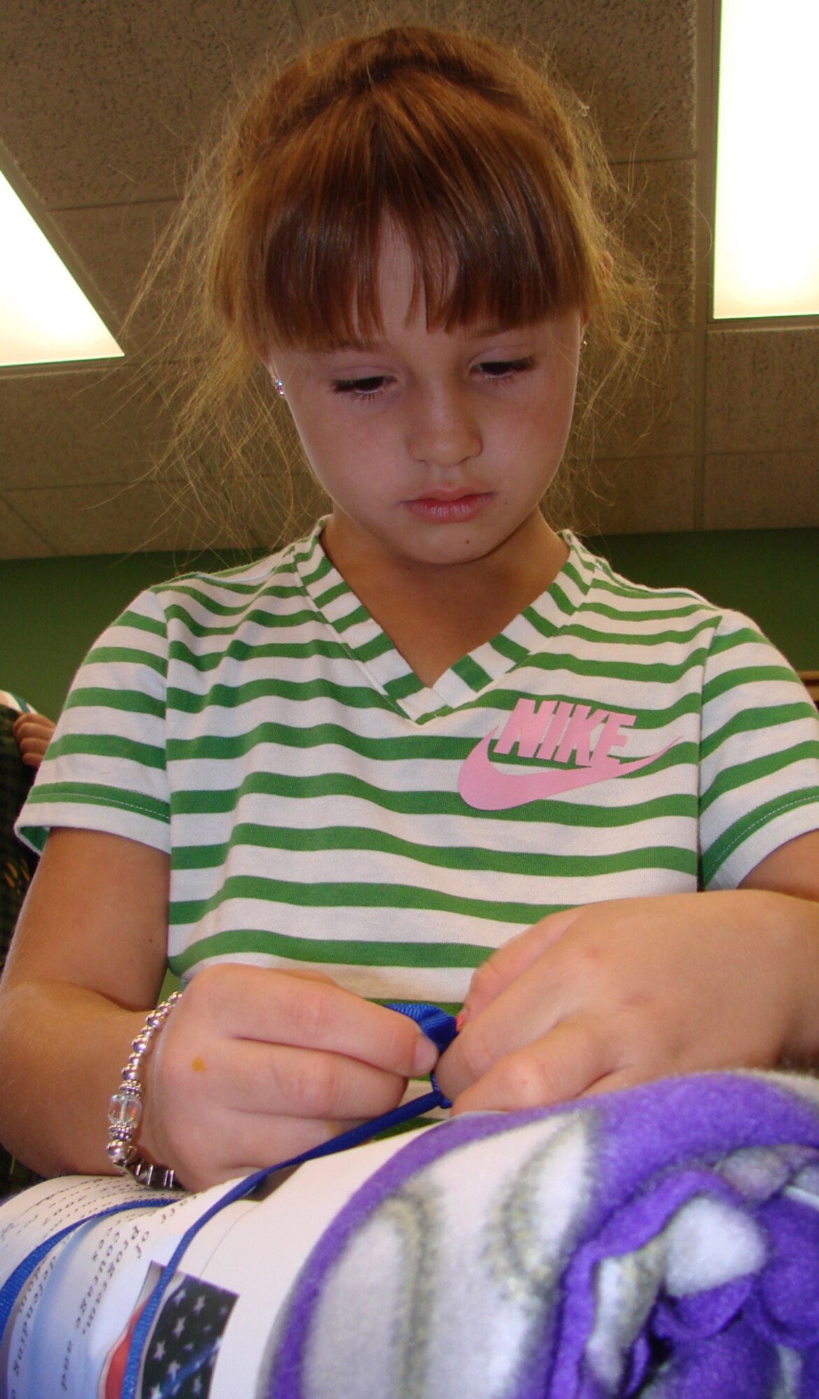 Macy VanKirk, 6, daughter of Amanda and Master Sgt. Mike Finnegan, 71st Flying Training Wing aircraft maintenance quality assurance evaluator, ties an appreciation certificate to a lap blanket to be given to a veteran for Make a Difference Day Oct. 27. The Vance Youth Center children made more than 100 blankets for veterans at the Oklahoma City VA Medical Center. (U.S. Air Force photo by Tech. Sgt. Mary Davis)