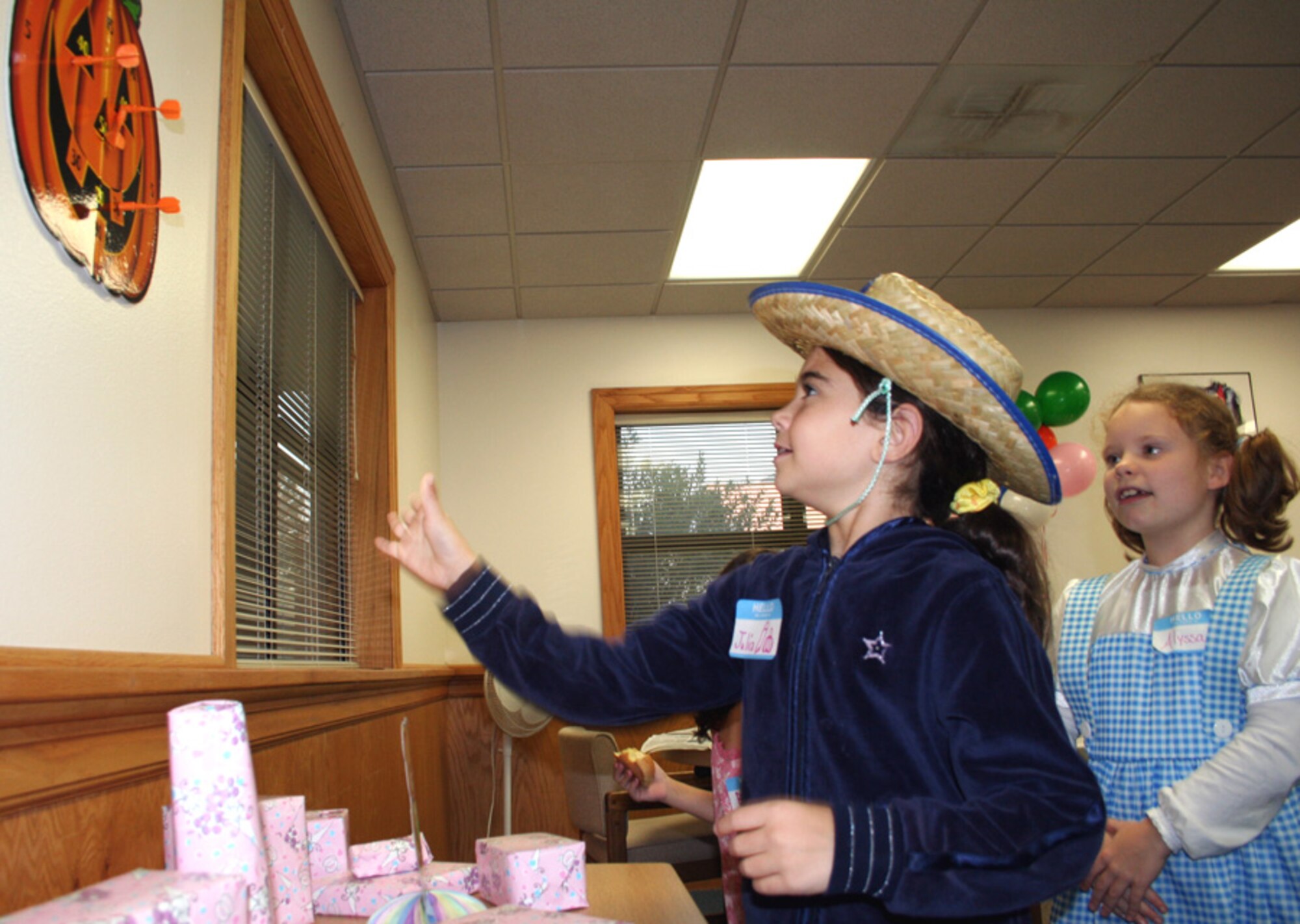 Eight-year-old Alyssa Landford watches on as eight-year-old Julia Rodriguez throws darts during the Hearts Apart Hobo Night Oct. 26. at the Airman & Family Readiness Center. The event was thrown by the A&FRC as a Halloween-alternative theme party designed to get family members of deployed and remotely assigned Airmen together for a night of fun. (U.S. Air Force photo by Tech. Sgt. Angela Shepherd)