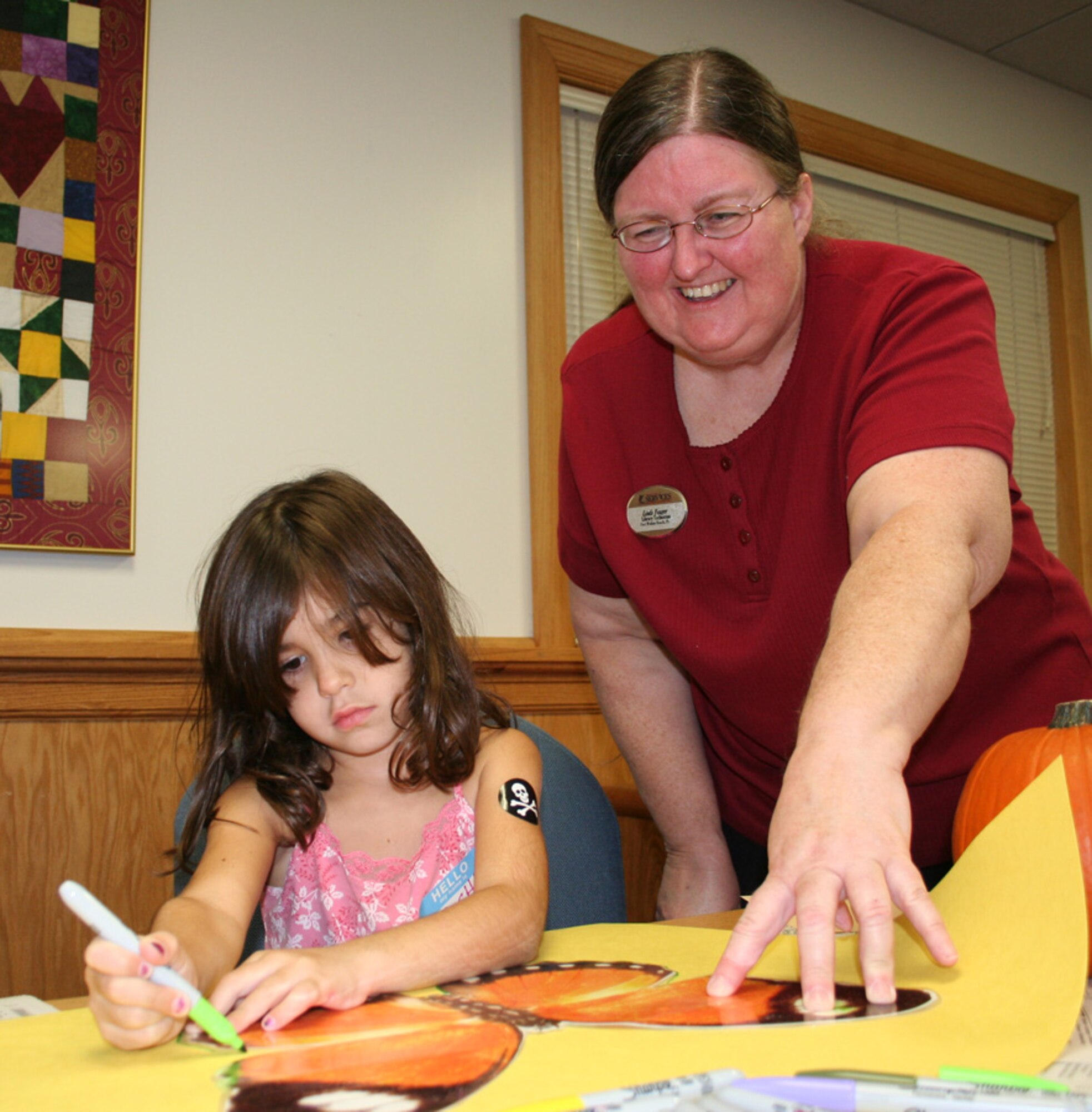 Rachel Rodriquez, 4, traces a butterfly stencil at the Hearts Apart Hobo Night Oct. 26. at the Airman & Family Readiness Center as Linda Yeager, a base library technician, holds it down. The event was thrown by the A&FRC as a Halloween-alternative theme party designed to get family members of deployed and remotely assigned Airmen together for a night of fun. (U.S. Air Force photo by Tech. Sgt. Angela Shepherd)