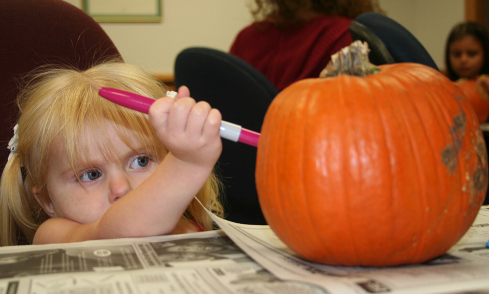 Two-year-old Cashlin Fleck decorates her pumpkin during the Hearts Apart Hobo Night at the Airman & Family Readiness Center Oct. 26. The event was thrown by the A&FRC as a Halloween-alternative theme party designed to get family members of deployed and remotely assigned Airmen together for a night of fun. (U.S. Air Force photo by Tech. Sgt. Angela Shepherd)
