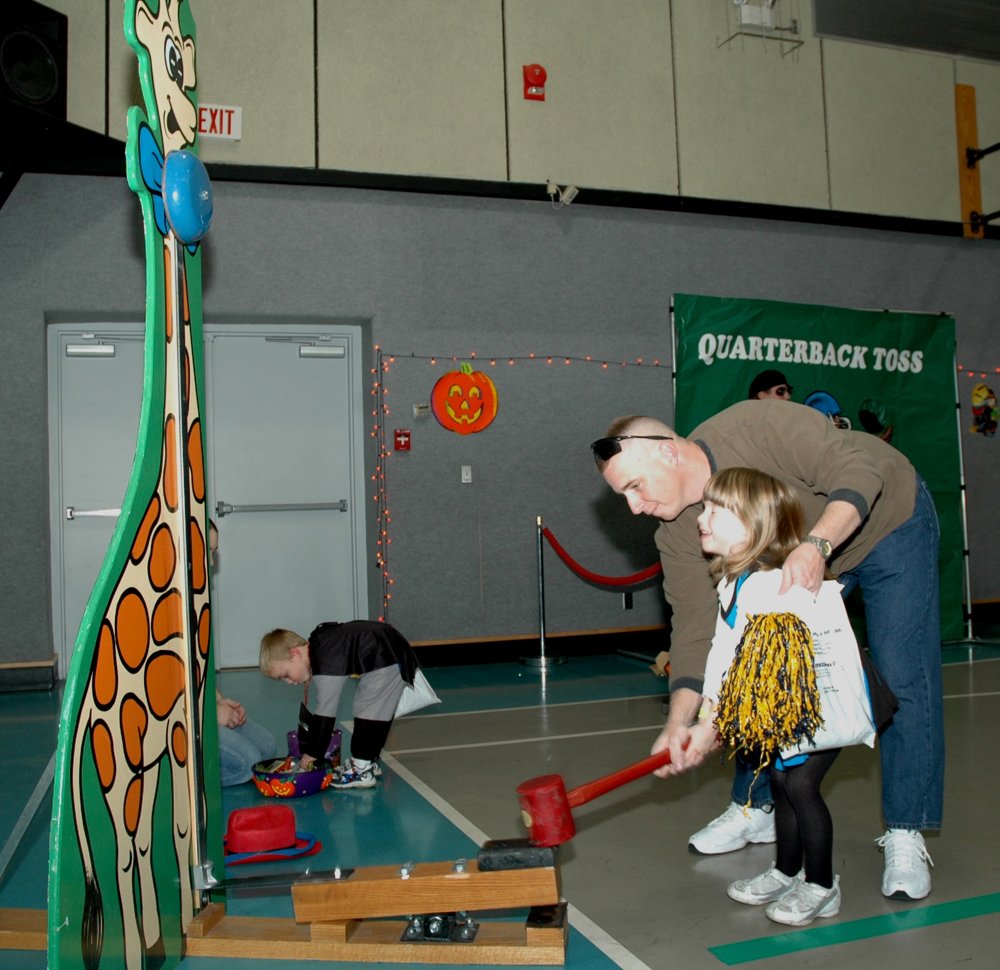 Tech. Sgt. Tom Hubal, 341st Civil Engineer Squadron, helps Little Warrior Kaitlyn, 5, ring the bell on the Giraffe Hammer at the Youth Programs Center's Fall Festival Oct. 26. (U.S. Air Force photo/Airman 1st Class Emerald Ralston)

