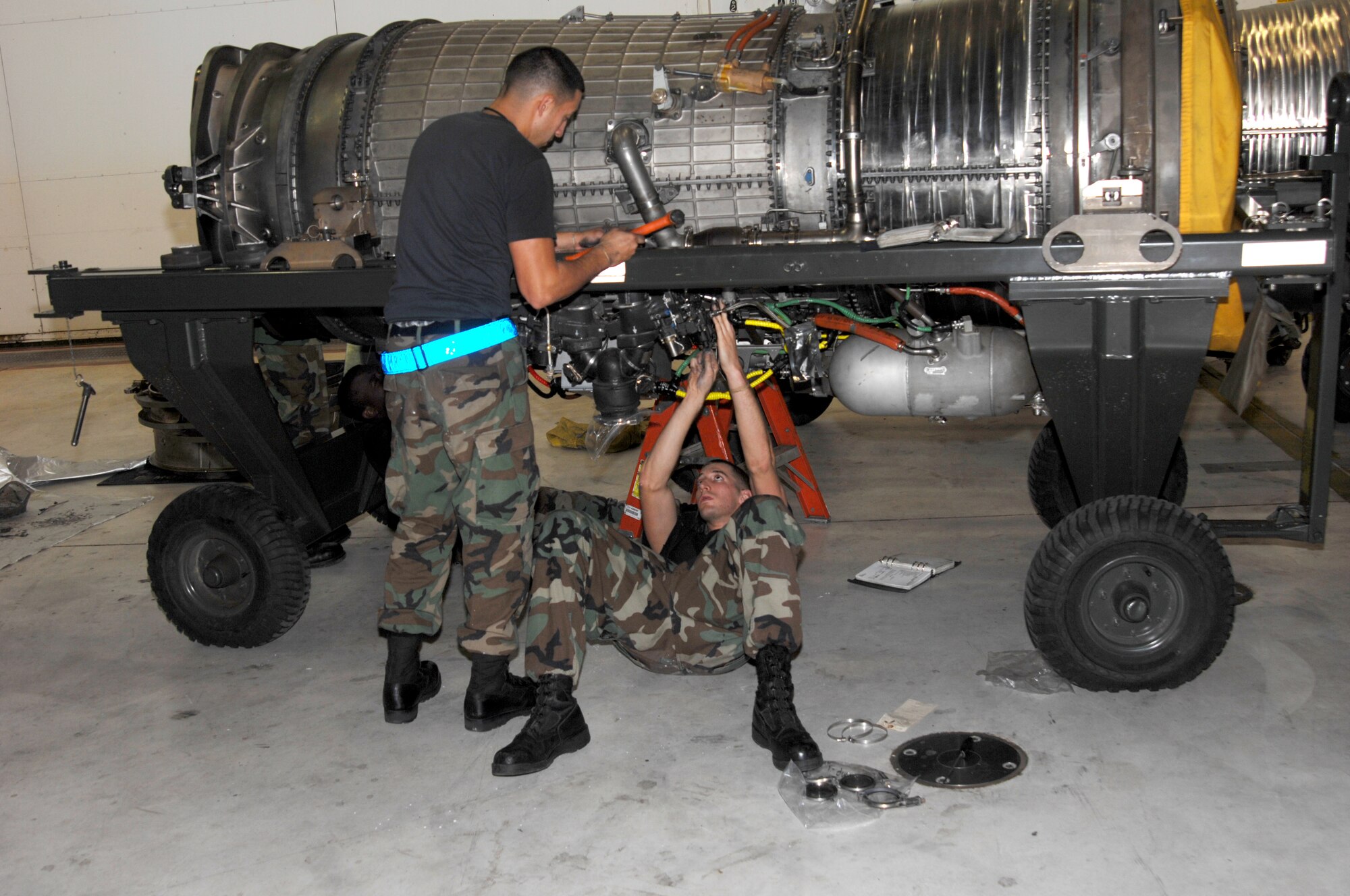 WHITEMAN AIR FORCE BASE, Mo. – Senior Airman Gary Thornhill (right) and Airman 1st Class James Mendrop, 509th Aircraft Maintenance Squadron, hammer Y-duct clamps to create a proper seal and apply the proper torque to the clamp bolts on a GE-F118 engine in preparation for installation Oct. 24.(U.S. Air Force photo/Tech. Sgt. Samuel A. Park)