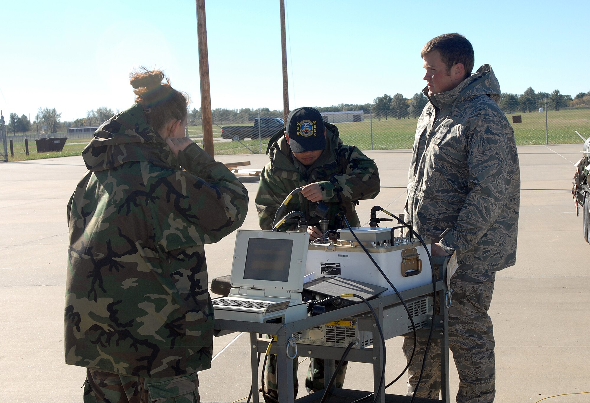 WHITEMAN AIR FORCE BASE, Mo. -- (Left to right) Senior Airman Catrina Maxwell, Airman 1st Class Mark Cruz and Senior Airman Keith Ellis, 509th Munitions Squadron, conduct an initial setup of a test set to perform a software upgrade on the tailkits of Joint Direct Attack Munitions Oct. 24. The crew completed the upgrade on the wing's immediate response war reserve material. (U.S. Air Force photo/Tech. Sgt. Samuel A. Park)