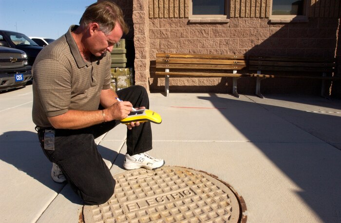 Roger Clarke, Geospatial information manager with the 99th Civil Engineer Squadron, demonstrates logging a man-made landmark, in this case an electrical manhole, into the mobile Geo XT global positioning system Oct. 30, Nellis AFB, Nev.  After logging the point into the handheld unit, Mr. Clarke will return to his office and upload the information into the Nellis GeoBase program, where the information will be readily available for all GeoBase users. (U.S. Air Force photo by Airman 1st Class Ryan Whitney)