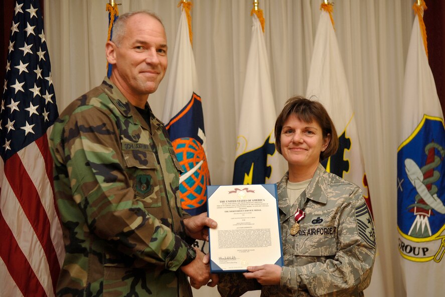 HANSCOM AFB, Mass. -- Col. Tom Schluckebier (right), 66th Air Base Wing commander, stands alongside Chief Master Sgt. Lisa Sirois after presenting her with a Meritorious Service Medal during her Farewell Social Oct. 30. Chief Sirois, who has served as the 66th Air Base Wing and Electronic Systems Center command chief since October 2005, is scheduled to leave Hanscom in November for a year-long short tour to Manas Air Base, Kyrgyzstan. (U.S. Air Force photo by Jan Abate.)