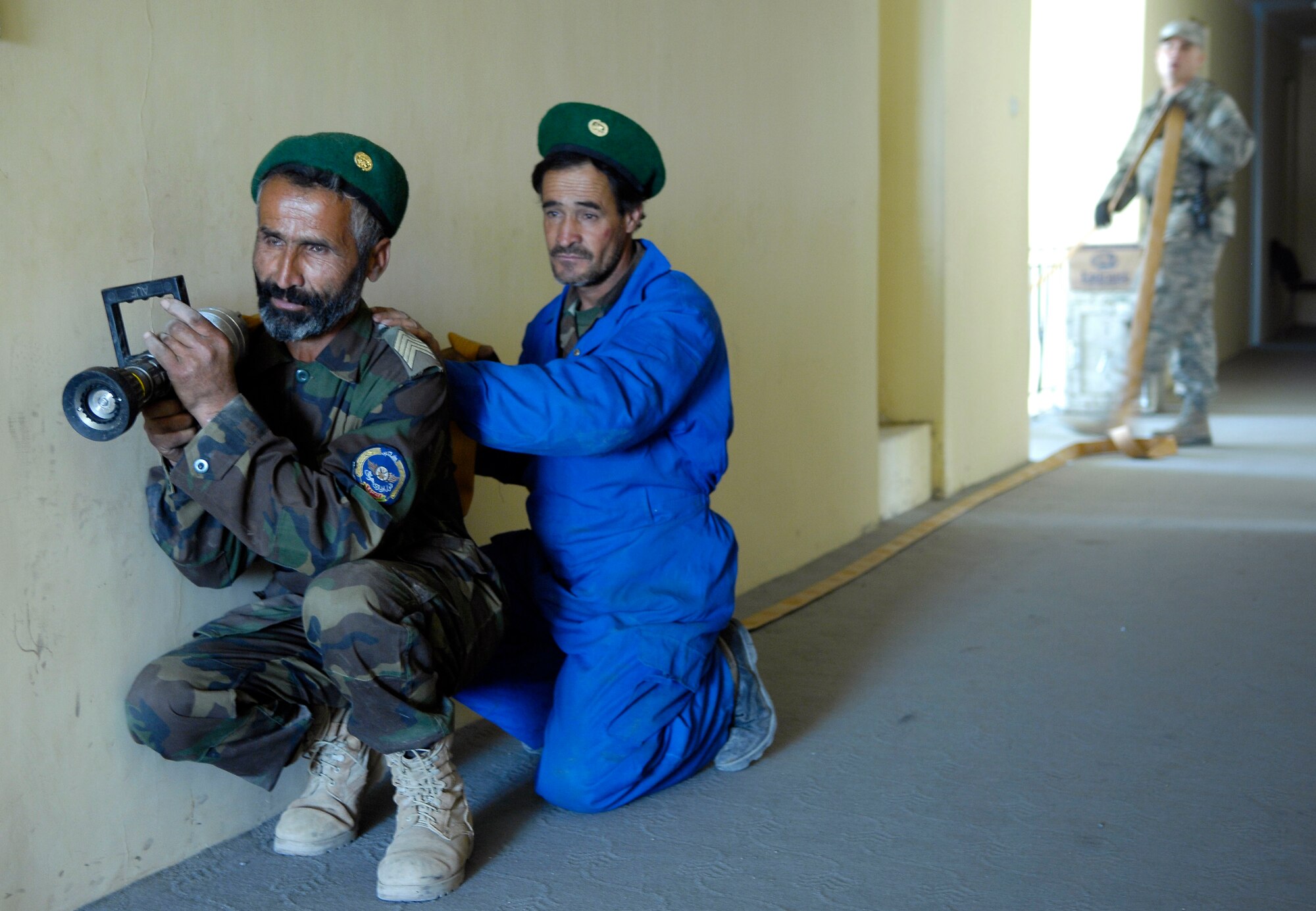 Master Sgt. Tim Rickard looks on as (front) Sgt. Basir and Sgt. Asadullah, Afghan National Army Air Corps firefighters, post in the hallway of a building at Kabul International Airport, Afghanistan, during a training exercise here.  The firefighters are training with Air Force mentors to build their fire protection capability.  Sergeant  Rickard is deployed here from the 36th Civil Engineering Squadron, Andersen Air Force Base, Guam.  (U.S. Air Force photo by Staff Sgt. Brian Ferguson)