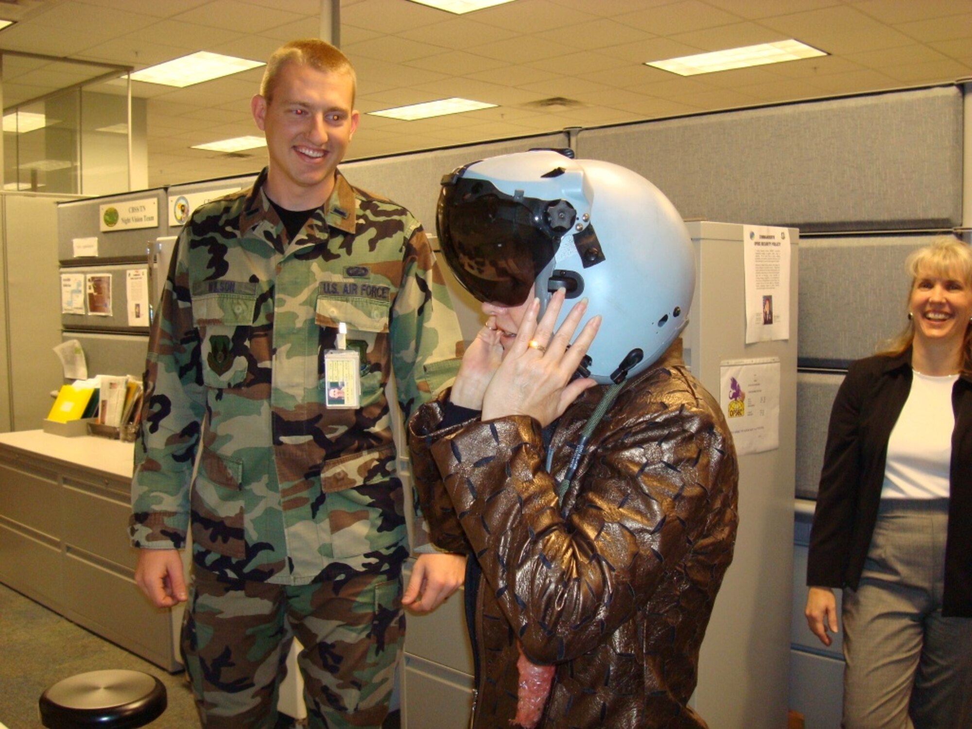 Ms. Peyton tries on the Joint Helmet Mounted Cueing System while 1st Lt. Cary Wilson looks on. (Air Force photo by Capt. Greg Justice)