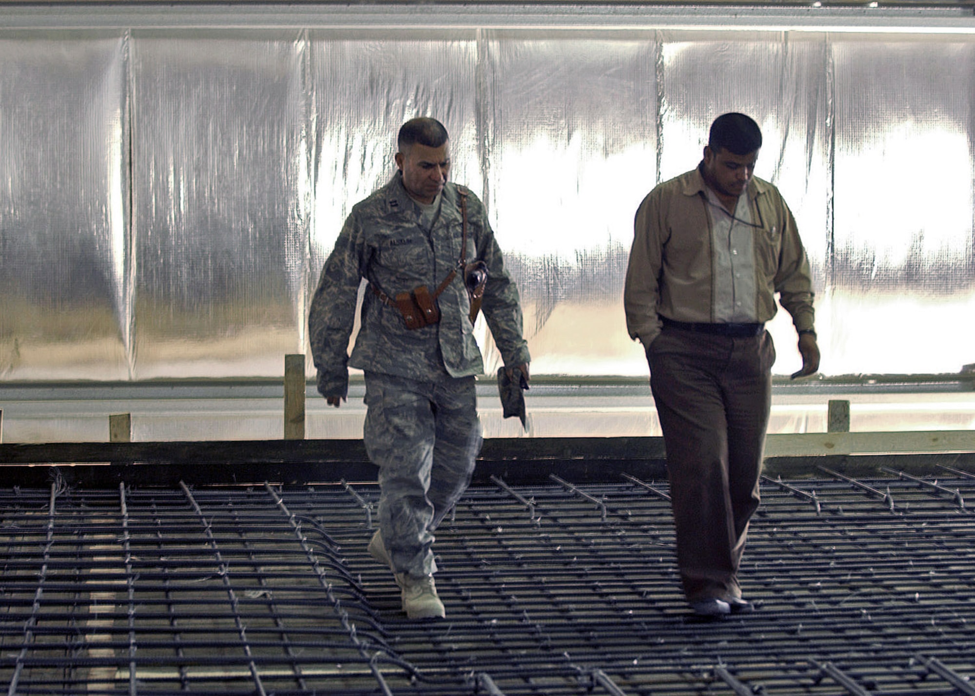 Capt. Rasul Alsalih, a project officer for the 732nd Expeditionary Civil Engineer Squadron, discusses a construction project with an Iraqi national. An Iraqi by birth, Captain Alsalih fought against Saddam Hussein shortly after Desert Storm and found refuge in an Army camp in Saudi Arabia. He was educated in the U.S. before seeking a commission in the Air Force. He was one of four servicemembers recognized as an "Outstanding American by Choice" this year. (U.S. Air Force photo/Airman 1st Class Jonathan Snyder)