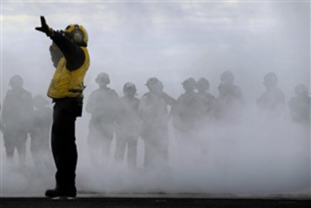 An aircraft director positions an aircraft on one of the Nimitz-class aircraft carrier USS Abraham Lincoln's steam-powered catapults during flight operations on the ship's flight deck while under way in the Pacific Ocean Oct. 27, 2007. 