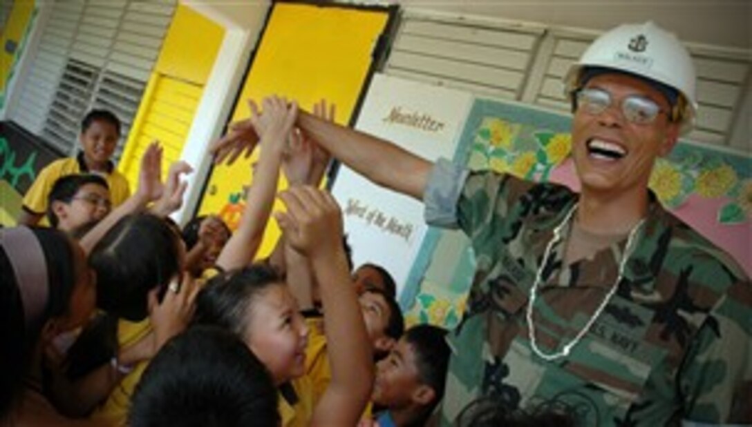 U.S. Navy Senior Chief Builder E. Dan Walker, senior enlisted leader of U.S. Naval Mobile Construction Battalion 1, Guam Detachment, shares a laugh with students of the Chief Brodie Memorial Elementary School in Guam, Oct. 26, 2007.  