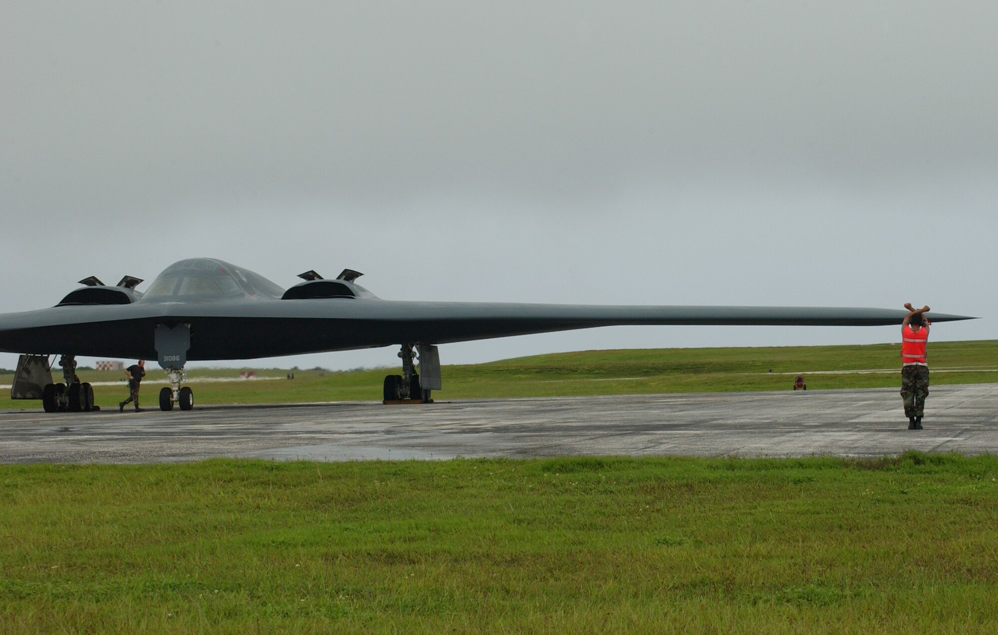 The last step in sending the B-2 to personally deliver some bad news to the enemy is, once again, in the hands of its crew chiefs. These Airmen are performing the last pieces of their procedures on getting this aircraft in the air. While one Airman removes the chocks from the wheels, another is preparing to guide the jet to its launch point. (Air Force photo/Senior Airman Brian Kimball)