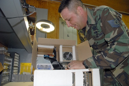 SOTO CANO AIR BASE, Honduras -- Tech. Sgt. Robert Russell, Armed Forces Network Honduras chief engineer, makes an adjustment to his "Frankenstein computer" he built from spare parts and a shipping box. The computer took about two weeks to build, since he had to wait on the glue to dry and cure after each computer component was added.  (U.S. Air Force photo/Tech. Sgt. Sonny Cohrs)