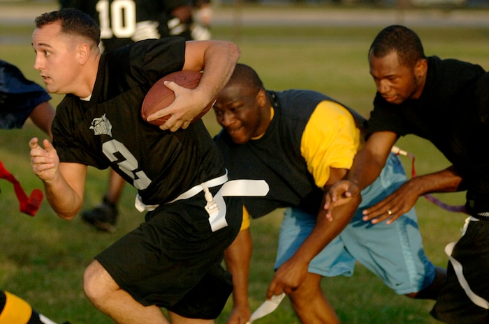 Neal French, 437th Civil Engineer Squadron, runs a pass downfield while opposing defenders from the Navy try to grab a flag during a flag football game Tuesday night on base. (U.S. Air Force photo/Airman 1st Class Nicholas Pilch)
