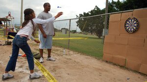 SOTO CANO AIR BASE, Honduras – Airman 1st Class Bryant Tunstalle watches Wendy Esmeralda, 15, throw darts at a dart board during the Joint Task Force-Bravo Army Forces Kid’s Day Oct. 27.  About 80 children came to the base from Hogar Tierra Santa Orphanage in Comayagua for games, swimming, a movie and lunch.  (U.S. Air Force photo by Staff Sgt. Austin M. May)