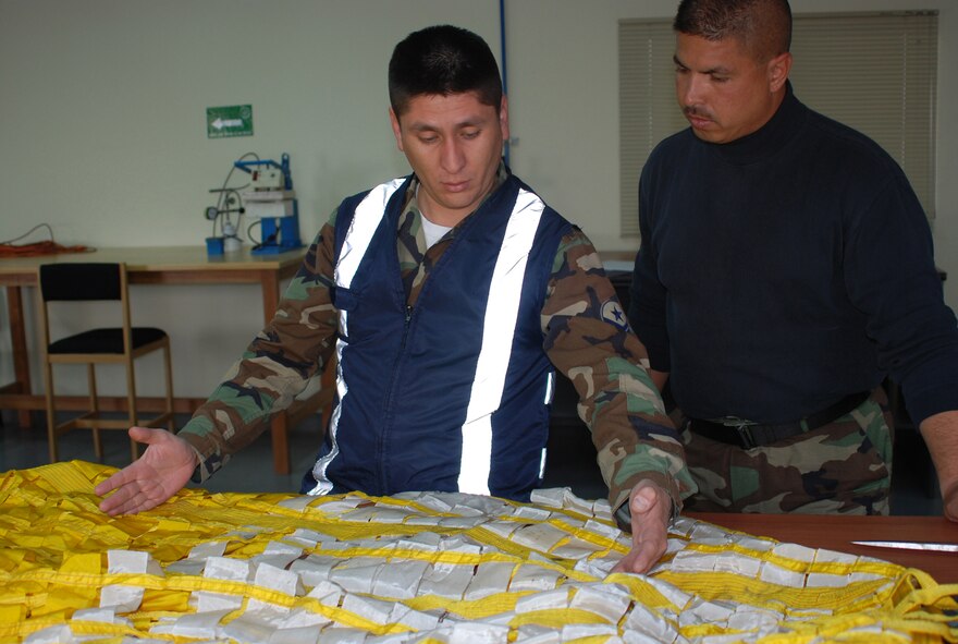 After explaining how to repair a torn parachute using parts from an old one, Master Sgt. Jose Rodriguez, right, 301st Maintenance Squadron, lets his Chilean counterpart make the repairs. (U.S. Air Force Photo/Laura Dermarderosian-Smith)