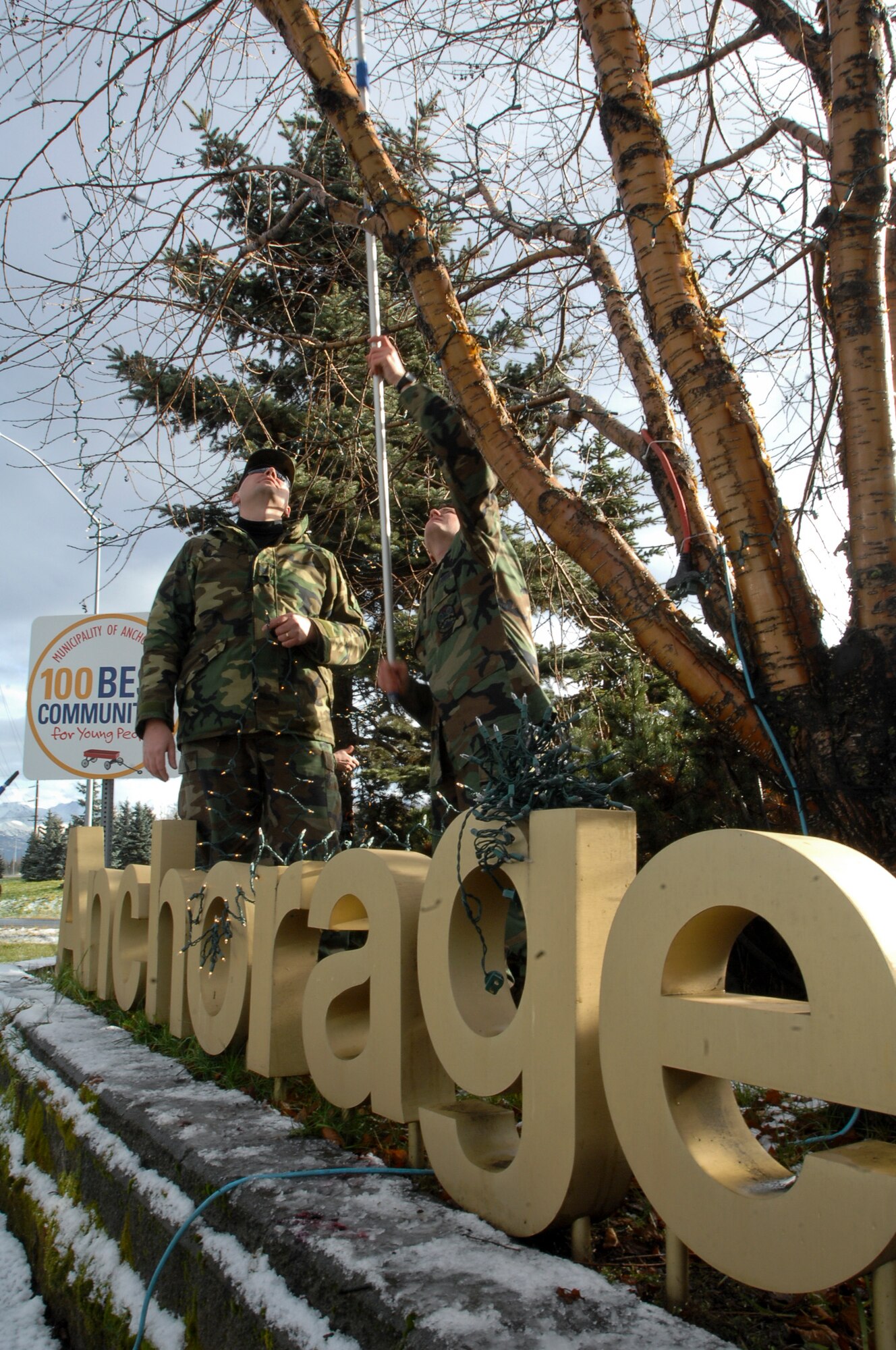 Airmen of the 3rd Civil Engineer Squadron string lights around the “Anchorage Welcomes You” sign near the Ted Stevens International Airport. (Photo by Airman 1st Class Tinese Treadwell)
