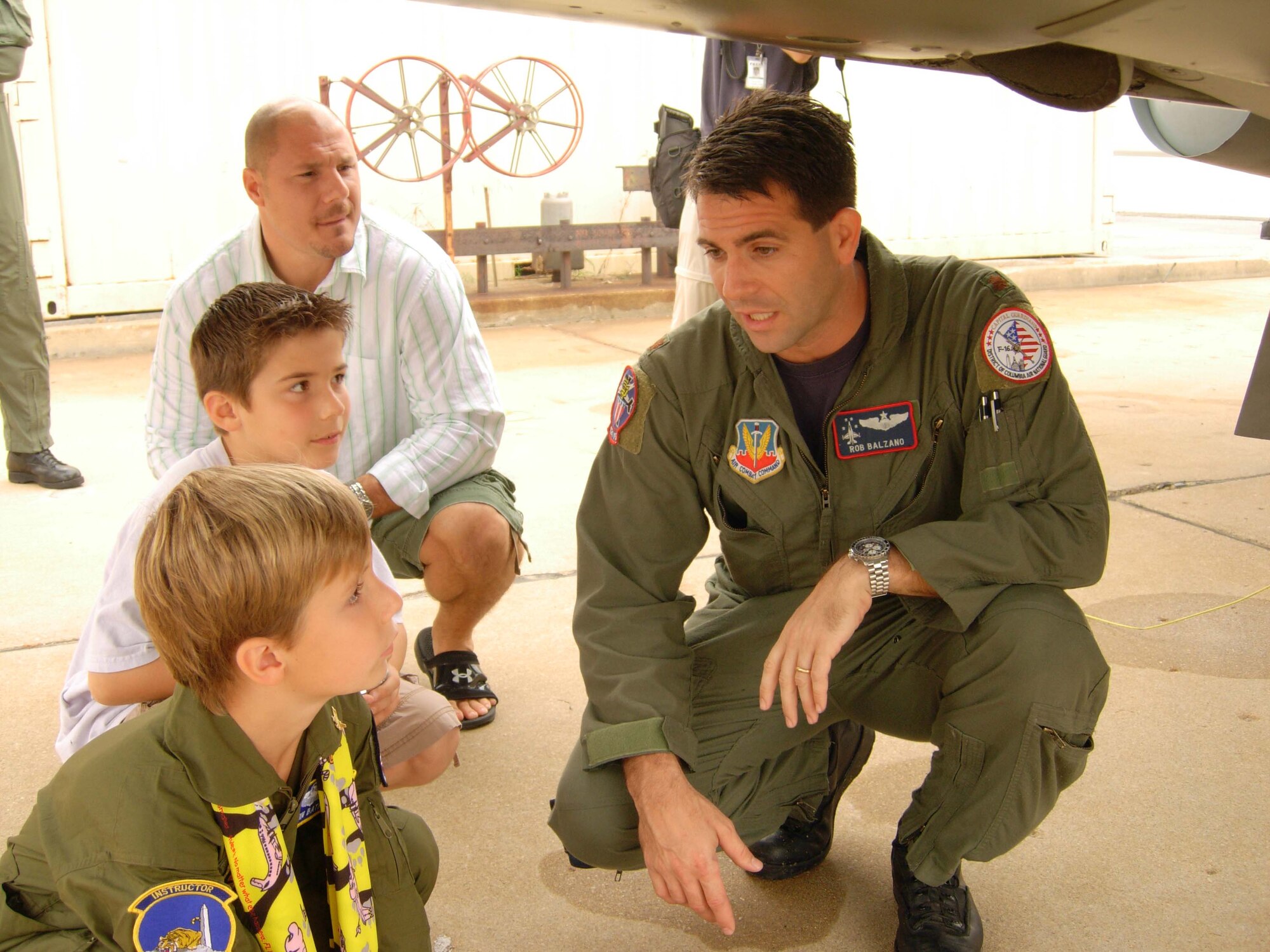 ANDREWS AIR FORCE BASE, Md. -- (Foreground) Griffin Bathras, 7, his brother Camden, 9, and their father, Patrick, listen as 113th Wing, 121st Fighter Squadron DC Air National Guard pilot Maj. Rob Balzano explains the mechanisms of an F-16 fighter jet during their tour. Griffin was the guest of honor as part of the D.C. ANG and 459th Air Refueling Wing joint venture "Pilot for a Day" here Oct. 4. The outreach program offers aircraft and squadron tours, lunch and full accommodations for children with serious or chronic conditions. The child also receives a personal pilot flight suit as he or she takes the pilot's oath. (U.S. Air Force photo/Staff Sgt. Amaani Lyle)