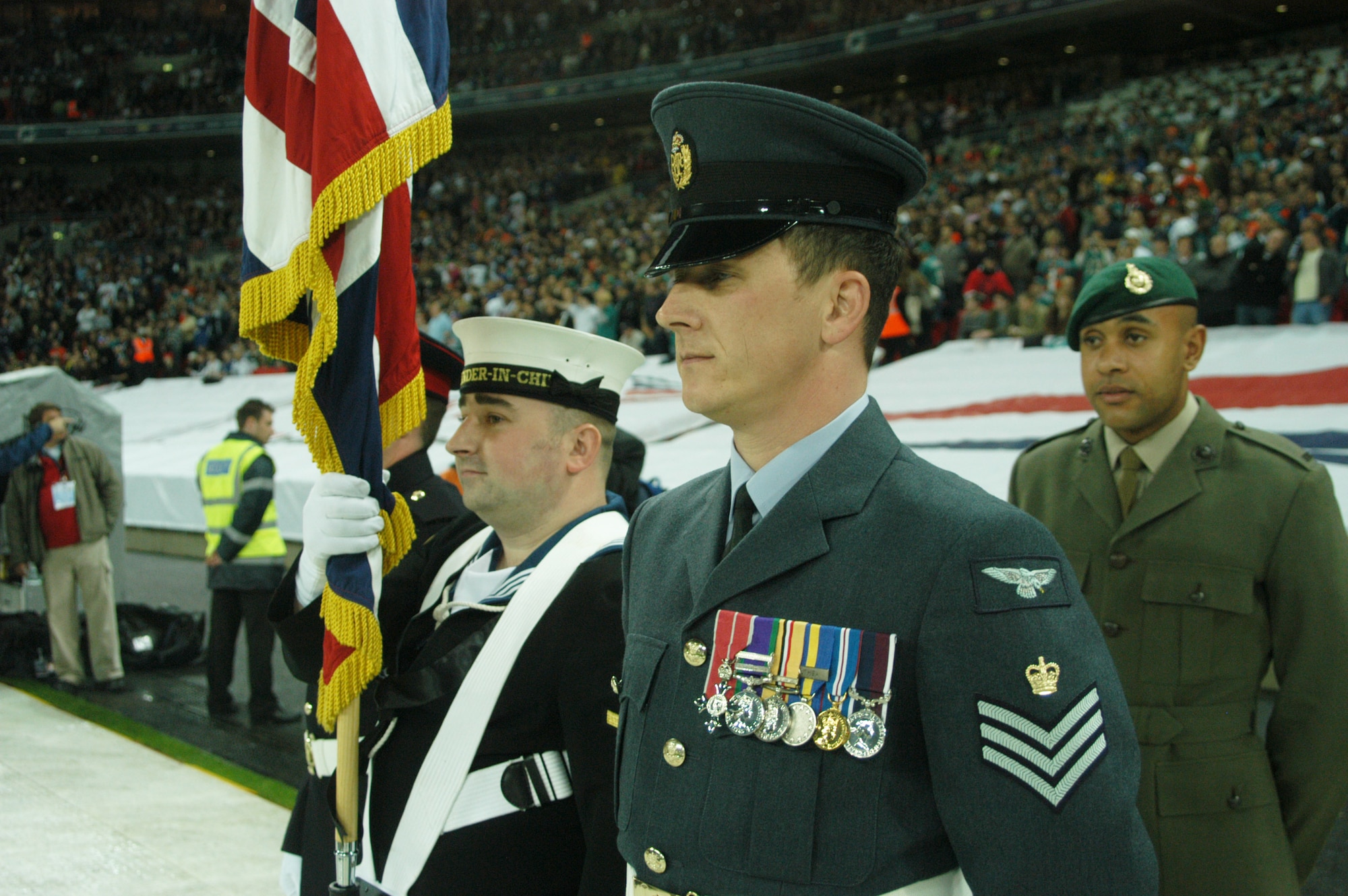 A British Joint Services Colour Guard performed along with the USEUCOM Joint Analysis Center Honor Guard at the October 28 first-ever regular season NFL game in London between the NY Giants and the Miami Dolphins.  There was a camaraderie between the two color guards who worked the choreography of the performance between them and included the JAC Team loaning their own British Flag and flag holster to the UK team to ensure performing symmetry as they marched from the respective 30 year lines to the center of the field during the singing of "God Save the Queen" and the "Star Spangled Banner." (USAF Photo by Staff Sgt. Jocelyn L. Rich)