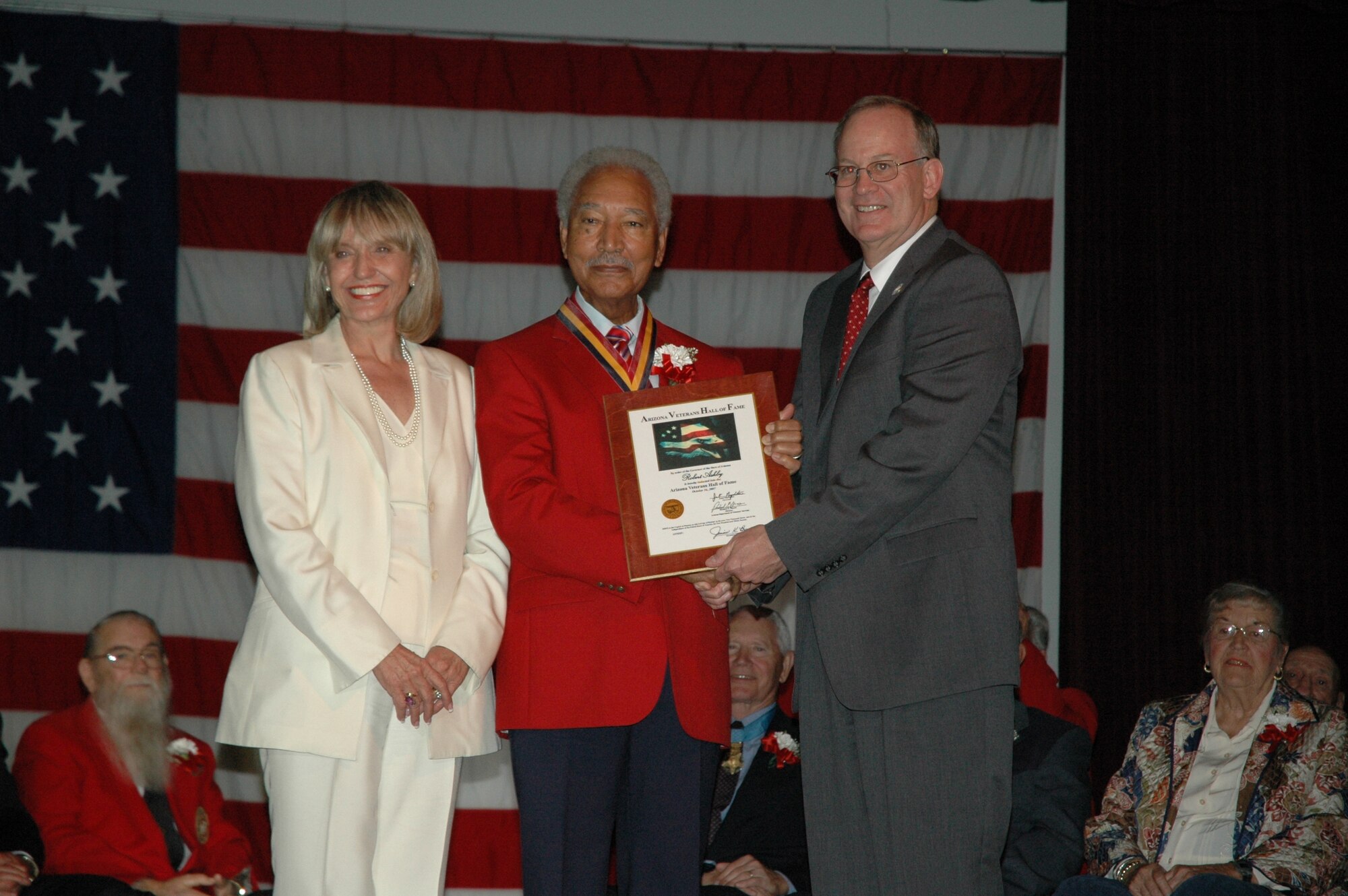 Lt. Col. (ret) Robert Ashby (center) accepts a plaque from Arizona Secretary of State Jan Brewer and Unified Arizona Veterans Chair Gary Fredricks during the Arizona Veterans Hall of Fame Induction Ceremony Oct. 26, 2007, in Phoenix. Colonel Ashby was one  of 20 Arizona veterans inducted into the Class of 2007. (U.S. Air Force photo/Tech. Sgt. Susan Stout)