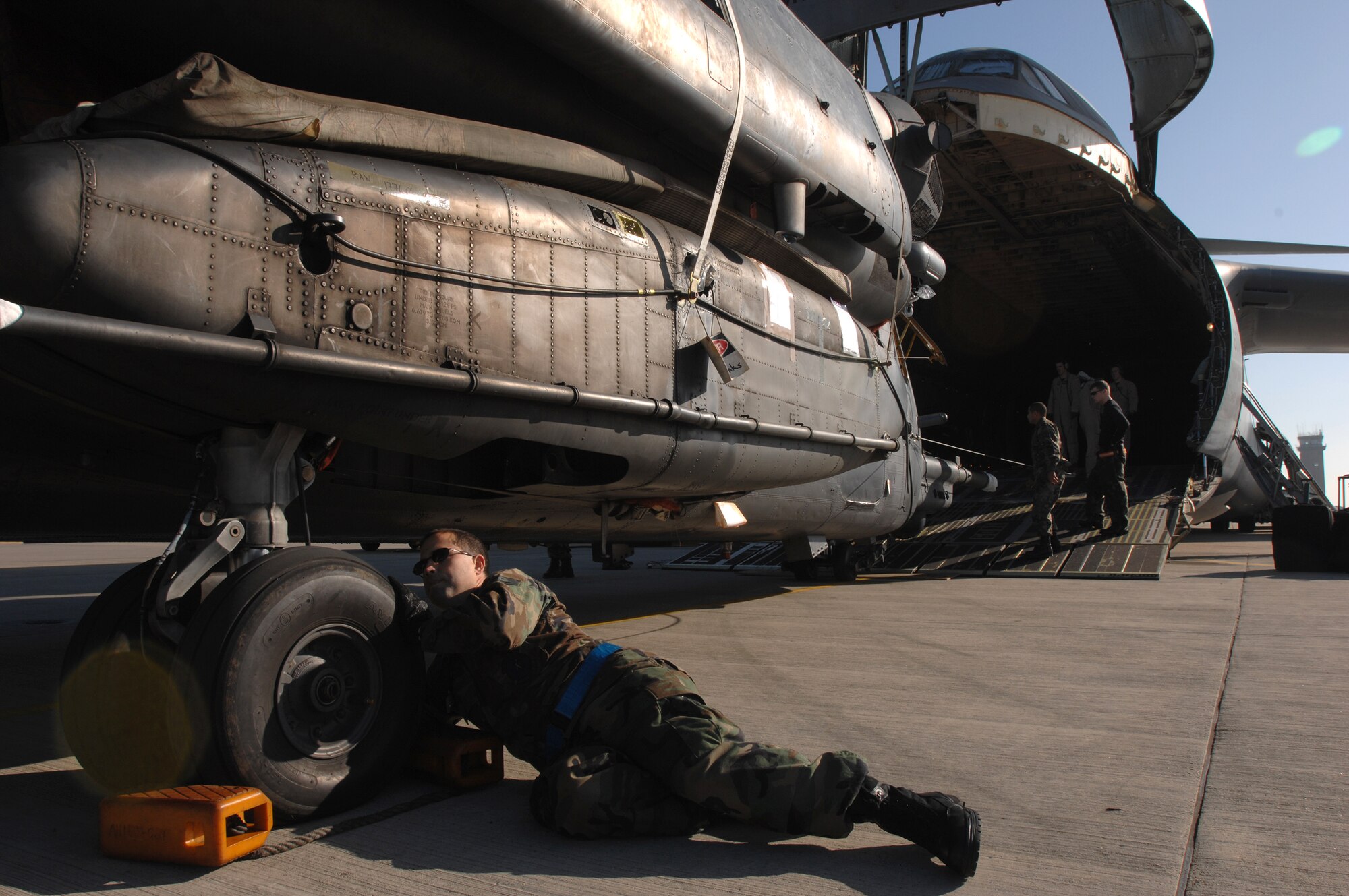 Tech. Sgt. Adrian Bergman, 352nd Maintenance Squadron crew chief,  inspects the tire height of a 21st Special Operations Squadron MH-53M Pave Low IV helicopter, destined for the the Aerospace Maintenance and Regeneration Group in Tucson, Ariz., prior to being loaded on a C-5 Galaxy from Travis Air Force Base, Calif., Oct. 5, 2007. A system of pneudraulics - a combination of liquid and air - controls the aircraft height during a complex load such as this, where only inches of space exist between the helicopter and C-5. (U.S. Air Force photo by Tech. Sgt. Tracy L. DeMarco)