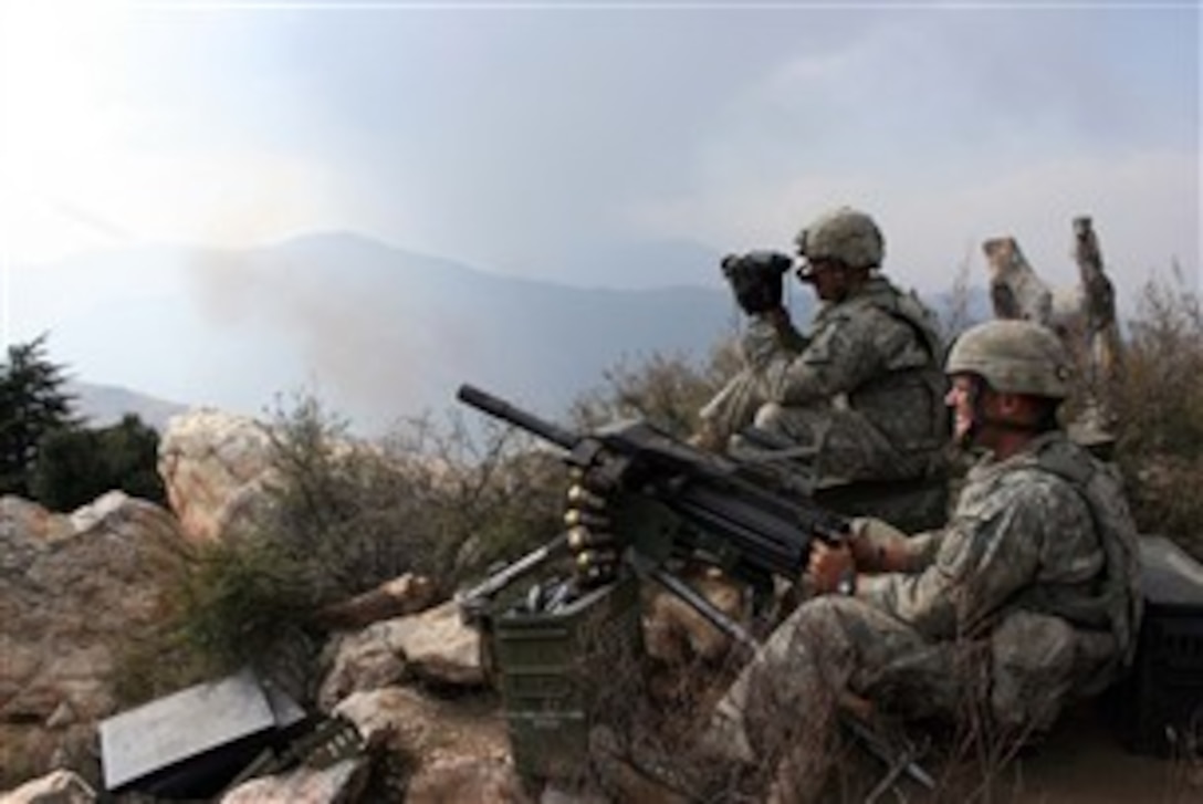 Army Sgt. Chad Mohr (left), watches rounds land on target as Spc. David Hooker (right), fires the MK19 grenade machine gun at a known insurgent position Oct. 24, 2007, during Operation Rock Avalanche in Kunar Province, Afghanistan.