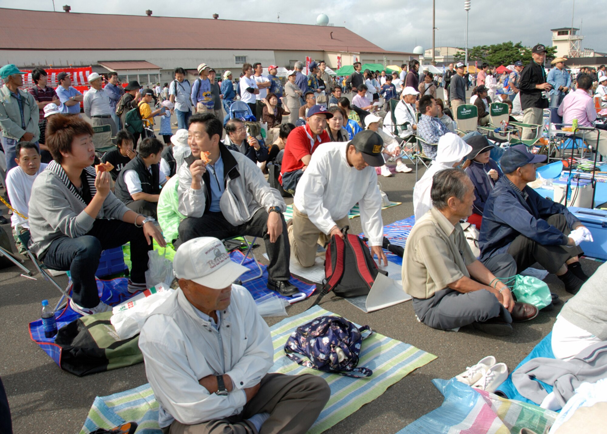 MISAWA AIR BASE, Japan -- Japanese guests make themselves comfortable on Misawa’s flightline and eat American pizza while waiting for 2007 Air Festival to begin September 2, 2007.  The Air Festival is held annually to promote relations between the American forces serving in Japan and the local citizens.  (U.S. Air Force photo by Senior Airman Laura R. McFarlane)(RELEASED)