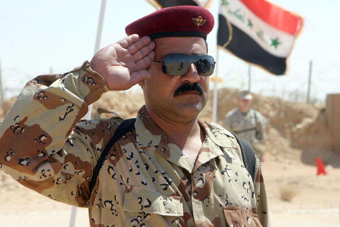 CAMP PHOENIX, Iraq ? An Iraqi soldier proudly salutes while a Marines stands at attention while the Iraqi national anthem sounds through speakers at the validation ceremony for 3rd Brigade, 7th Iraqi Army Division.  Traditionally, Marines do not salute in combat environments.