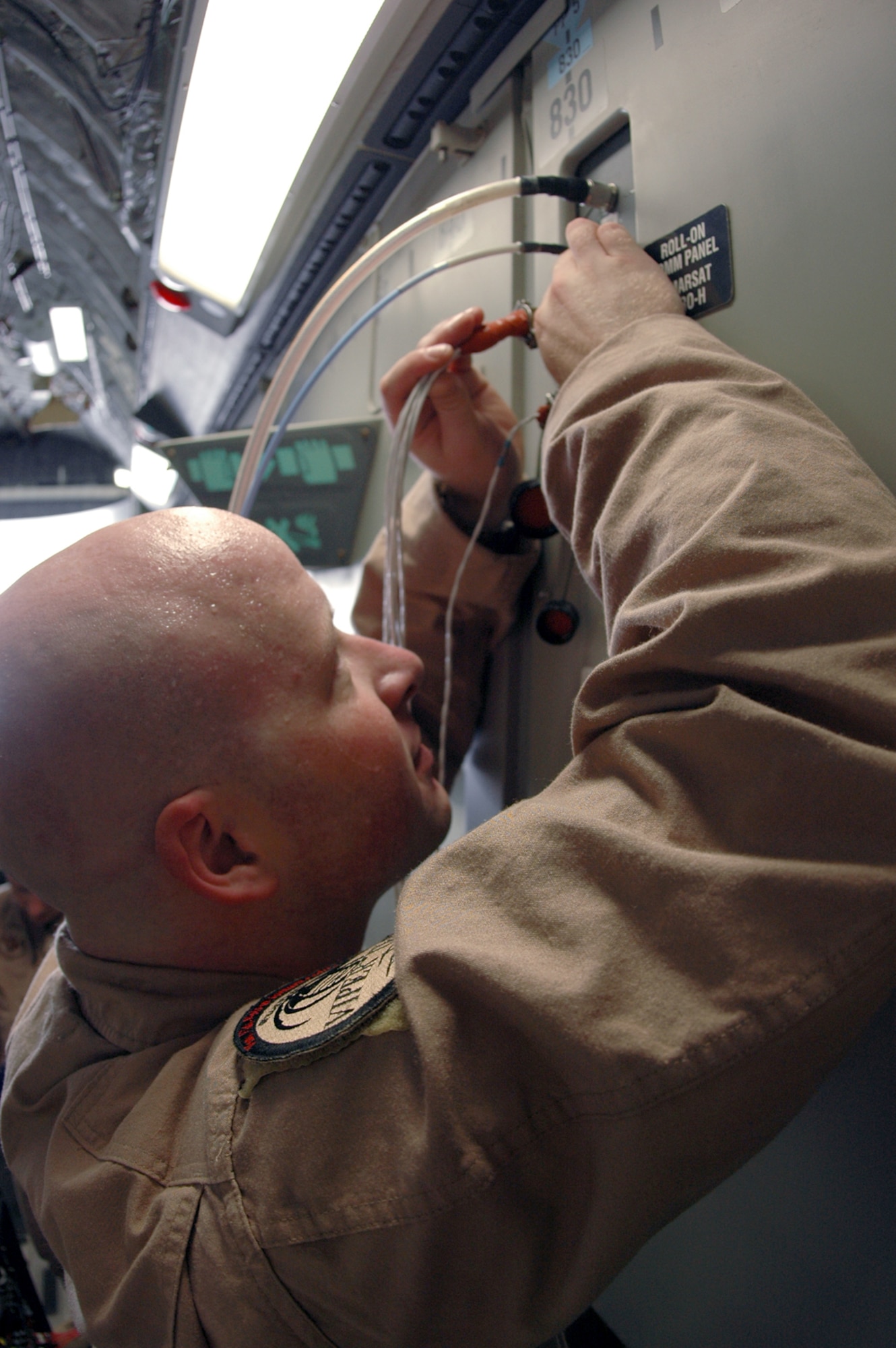 Tech. Sgt. Jason Moore, 379th Expeditionary Communications Squadron Viper Team member, connects commucations equipment aboard a C-17 before a mission Aug. 25. (U.S. Air Force photo by Senior Airman Clark Staehle)