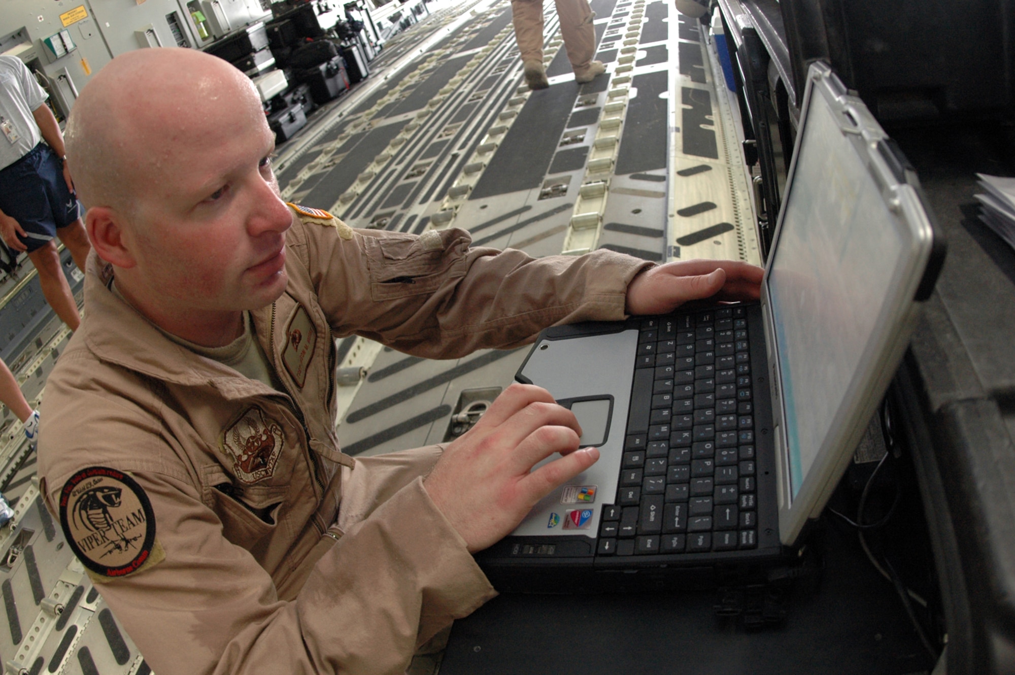 Tech. Sgt. Jason Moore, 379th Expeditionary Communications Squadron Viper Team member, uses a laptop to set up communications equipment aboard a C-17 before a mission Aug. 25. (U.S. Air Force photo by Senior Airman Clark Staehle)