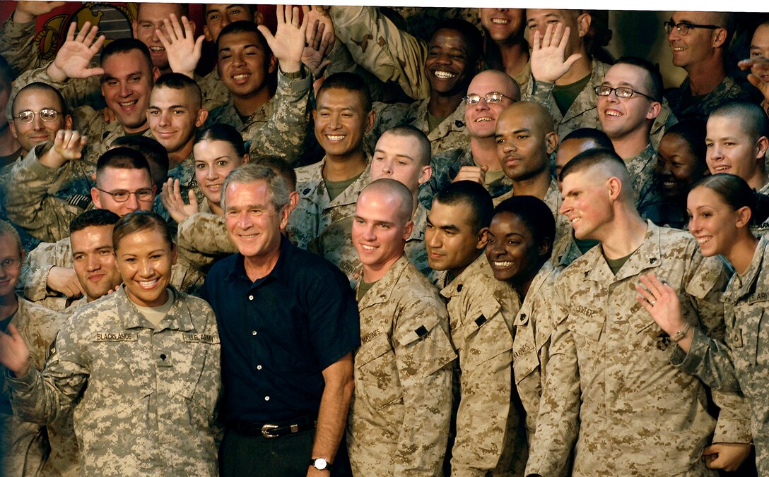 U.S. Service members gather around President George W. Bush during a visit to Al Asad Air Base, Iraq, Sept. 3, 2007.  Bush was joined by Secretary of Defense Robert M. Gates, Secretary of State Condolezza Rice, Chairman of the Joint Chiefs of Staff Gen. Peter Pace, U.S. Central Command Commander Adm. William J. Fallon, Commander of Multinational Forces-Iraq Gen. David Petreaus, Commander of Multinational Corps-Iraq Lt. Gen. Ray Odierno, and others.  