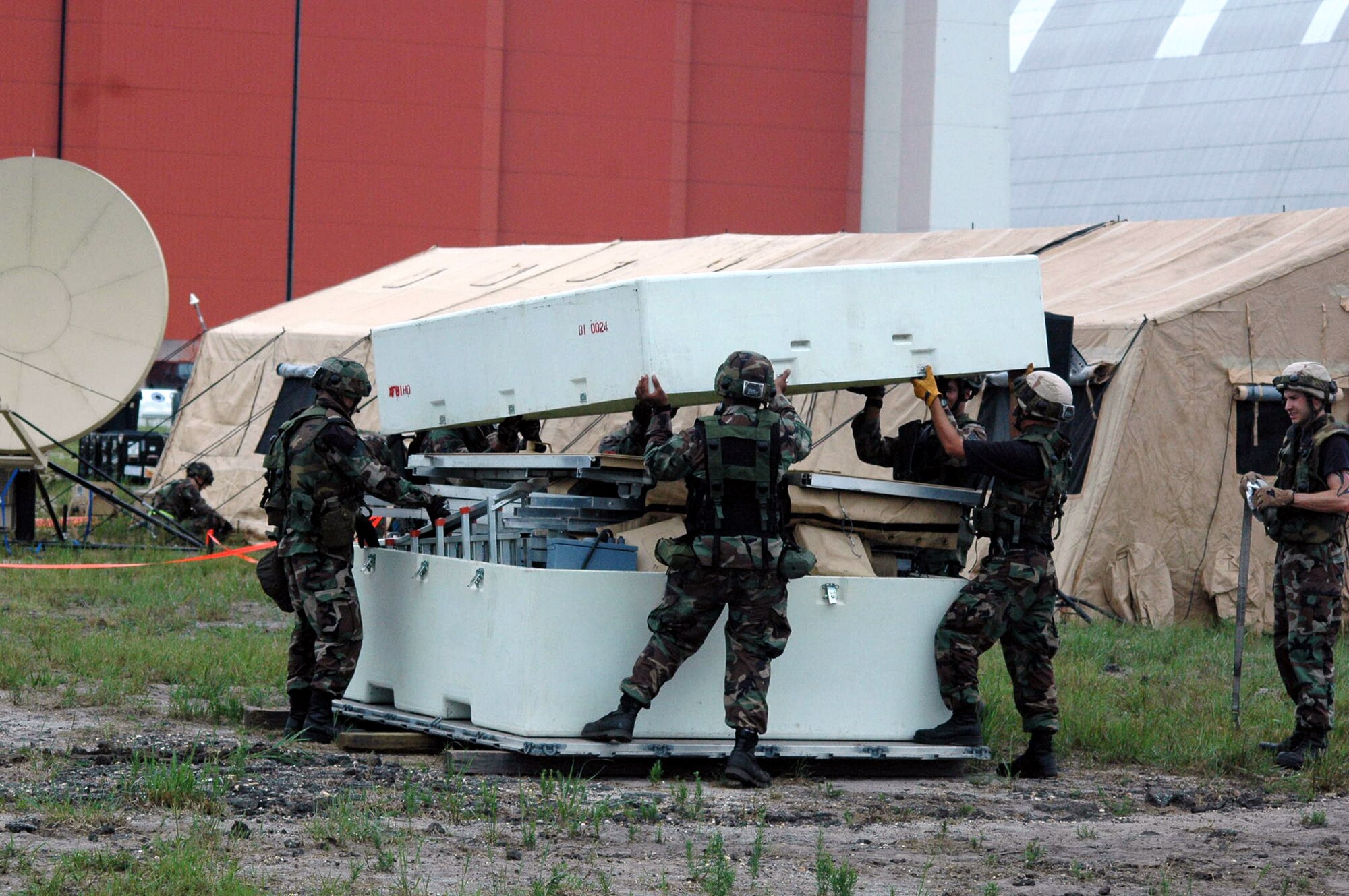 Airmen deployed as part of the fictional 421st Air Expeditionary Group lift the cover off of a cargo box containing a tent during operations for Air Force Exercise Eagle Flag 07-6 Aug. 26 at Naval Air Engineering Station Lakehurst, N.J. The exercise is coordinated by the Air Force Expeditionary Center's 421st Combat Training Squadron at Fort Dix, N.J. (U.S. Air Force photo/Tech. Sgt. Scott T. Sturkol)