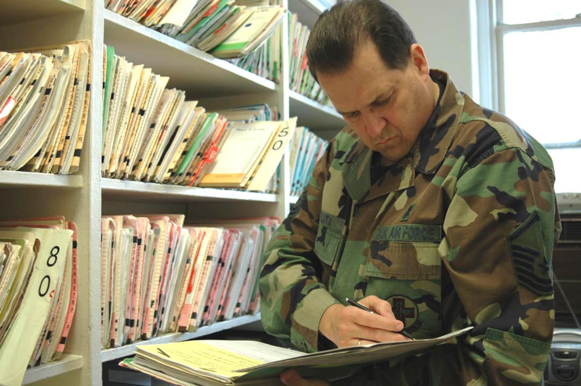 Master Sgt. Thomas Pluta, health service manager, in the record room, checks an Airman's medical record for immunization history. The record room contains over 600 individual medical records. (U.S. Air Force photo/Staff Sgt. Kevin Tomko)