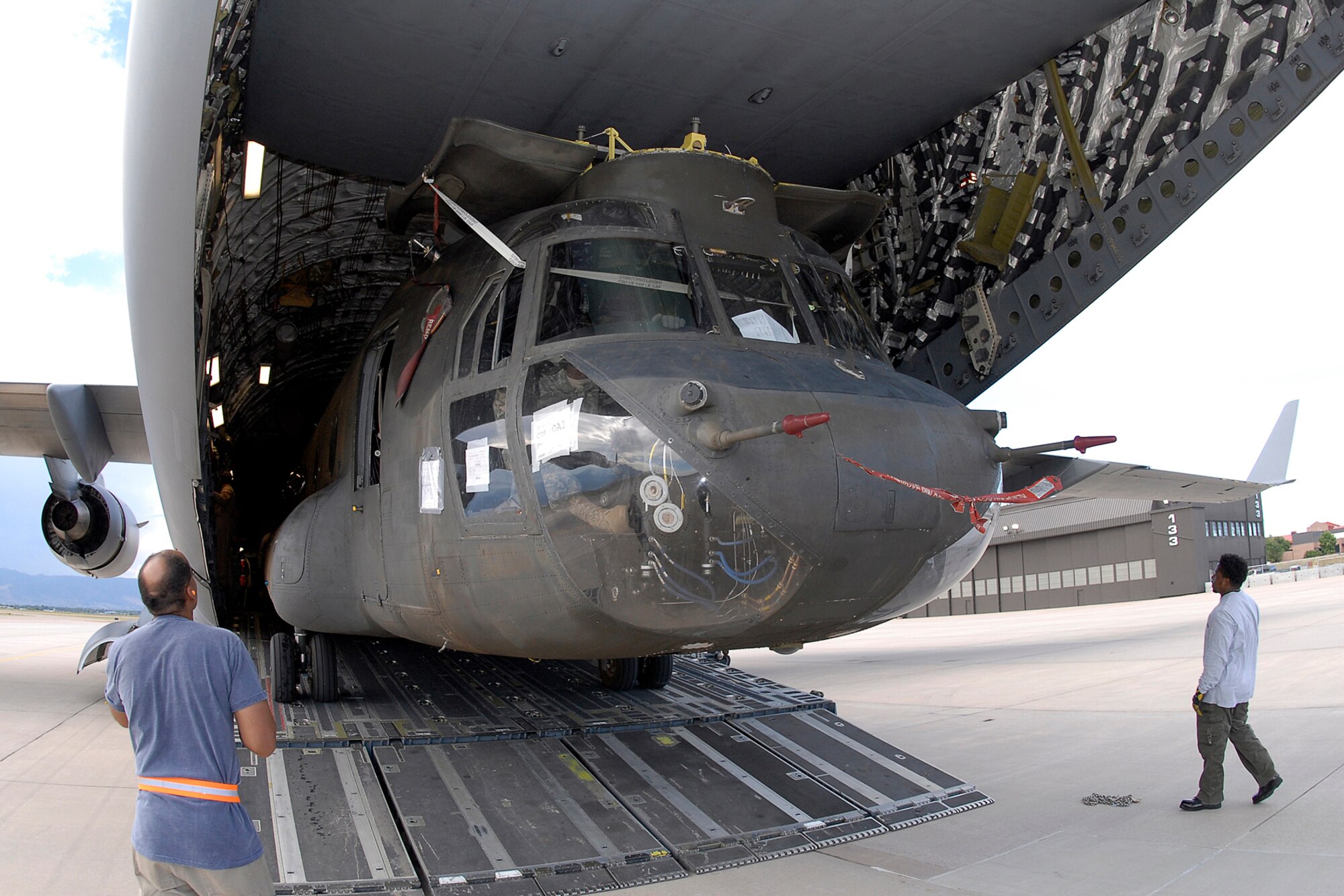 A Chinook CH-47D juts from the maw of a C-17’s cavernous cargo bay. Employees from Sikorsky Support Services Inc., and Soldiers from Company B, 3rd Battalion, 126th General Support Aviation Battalion, a National Guard unit from New York and Maryland, helped load the aircraft Aug. 30 for overseas deployment. A dozen of the helicopters were airlifted aboard C-17s through Peterson AFB in late August. (U.S. Air Force photo by Rob Bussard)